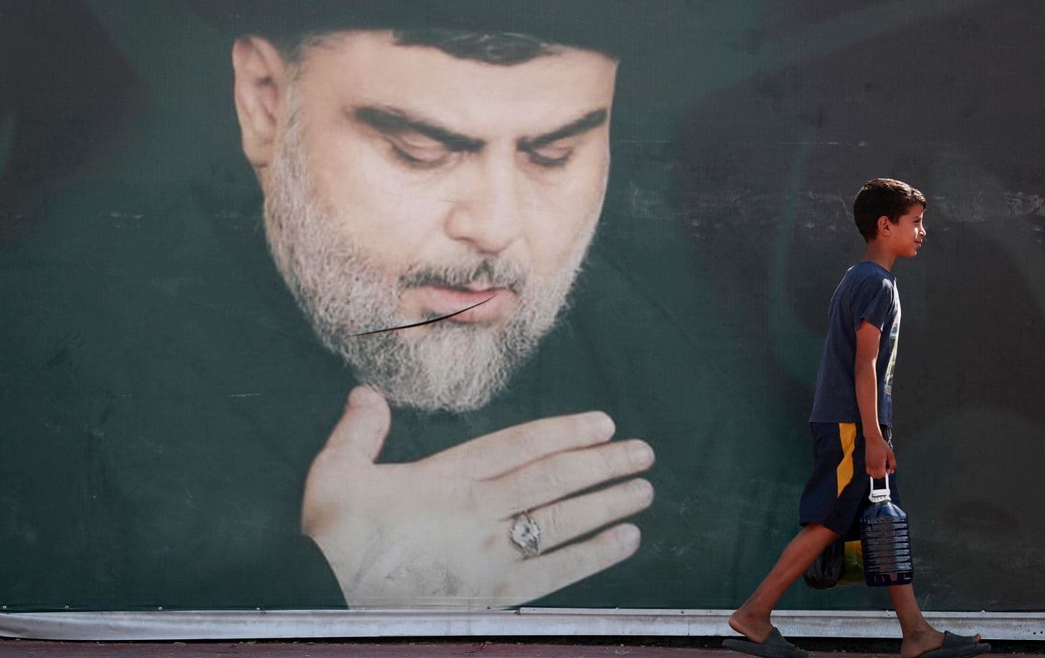 An Iraqi child walks past a poster of Shiite cleric Muqtada al-Sadr in Baghdad's Sadr City on October 17, 2021. Photo: Ahmad al-Rubaye/AFP