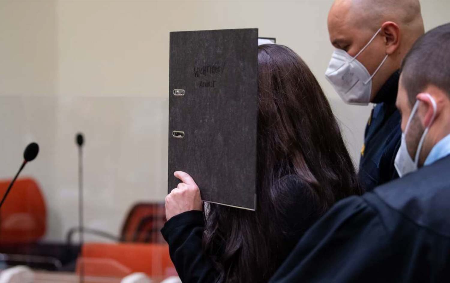 Jennifer Wenisch (centre), a German woman who joined ISIS, hides her face behind a folder as she arrives at court for the verdict of her trial in Munich, Germany on October 25, 2021. Photo: Sven Hoppe/DPA/AFP