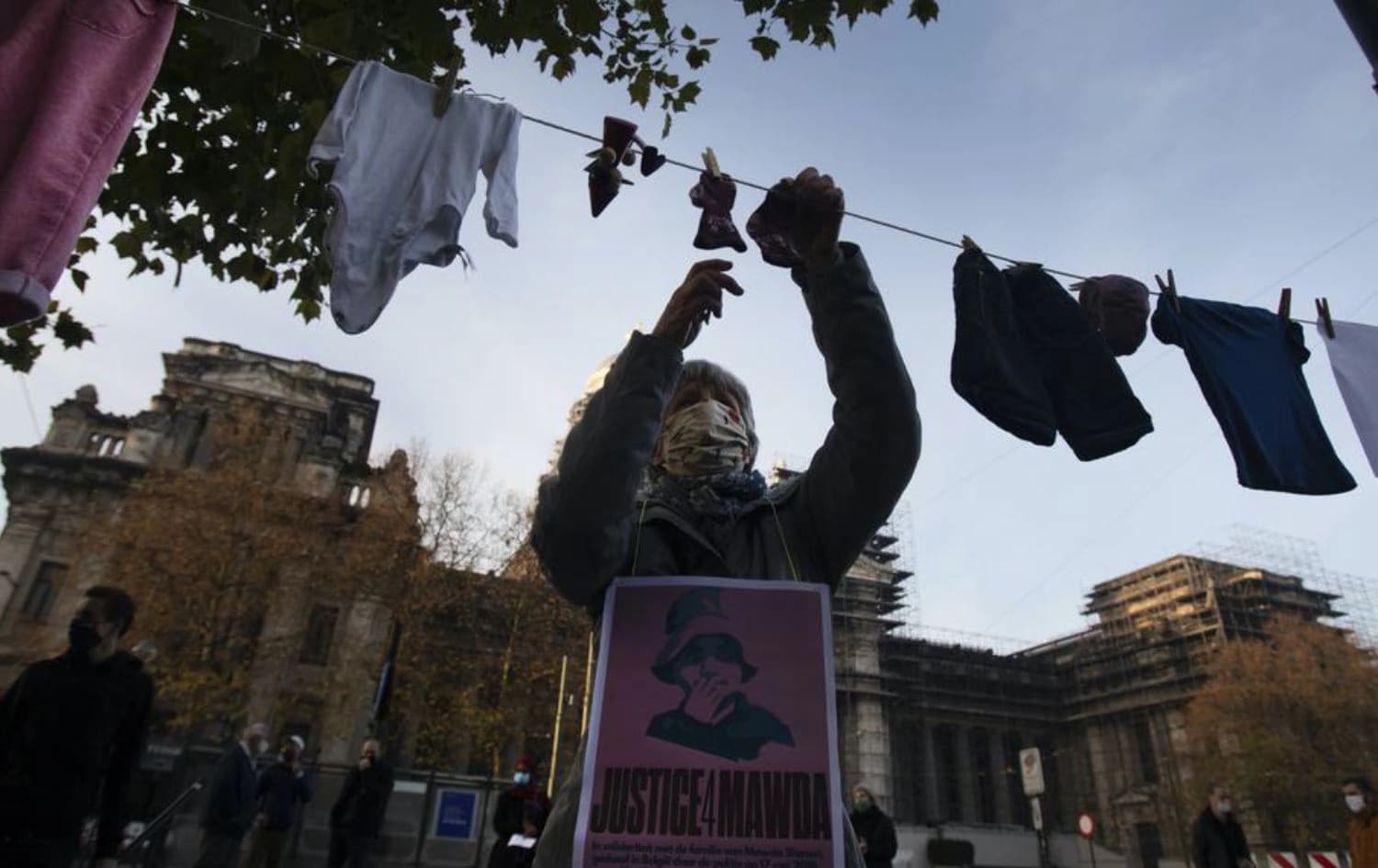 A woman hangs a piece of children’s clothing on a line during a solidarity event for Mawda Shawri at the courthouse in Brussels. Date: November 23, 2020.  Photo: AP 
