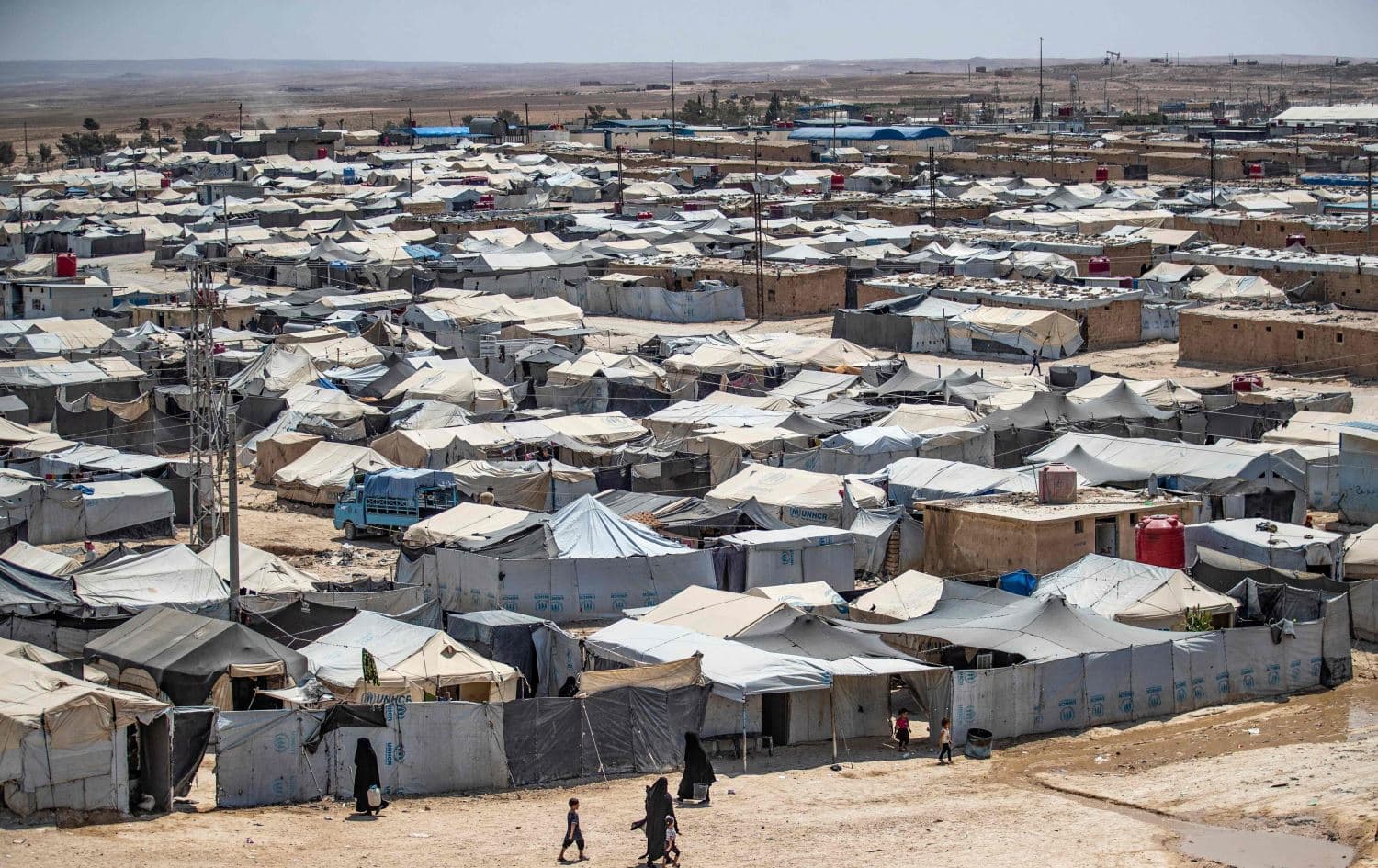 People walk among shelters at the Kurdish-run al-Hol camp, which holds relatives of suspected ISIS fighters, in Syria's Hasakah Province on August 2, 2021. Photo: Delil Souleimani/AFP