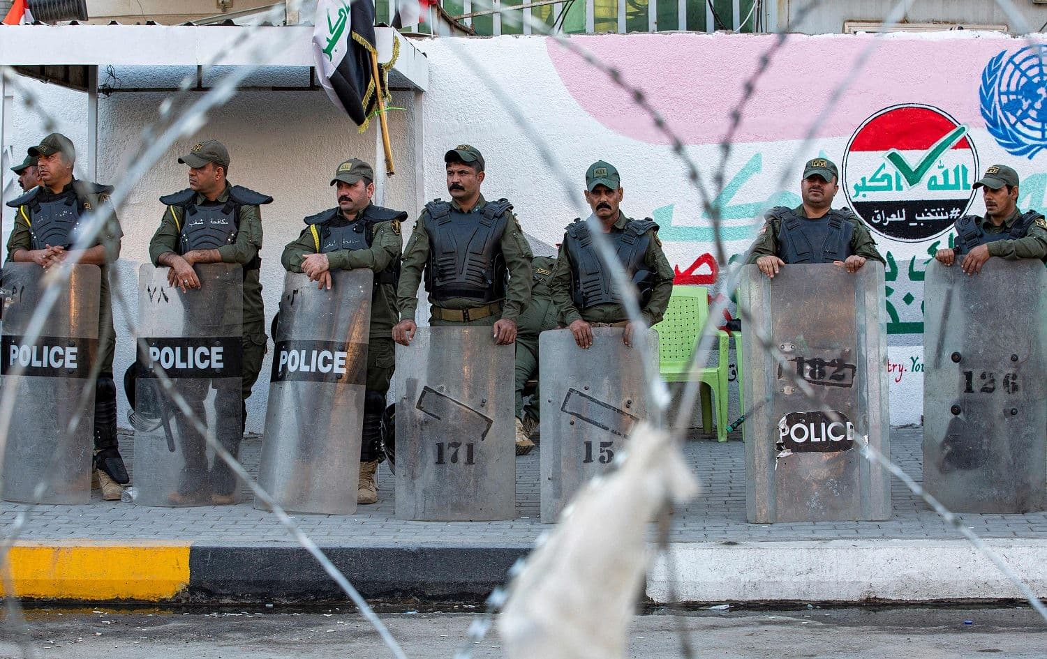 Iraqi security forces members stand guard outside the local headquarters of the Independent High Electoral Commission in Basra on November 9, 2021, as supporters of the PMF demonstrate nearby. Photo: Hussein Faleh/AFP