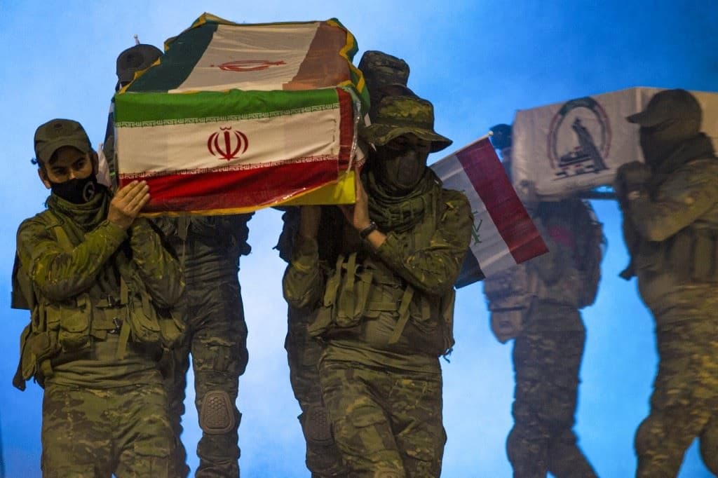 Actors carry coffins draped in the flags of Iran, Iraq, and the Hashed al-Shaabi as they re-enact the 2019 funeral of Iranian General Qasem Soleimani during a play in the southern city of Basra on December 29. Photo: Hussein Faleh / AFP