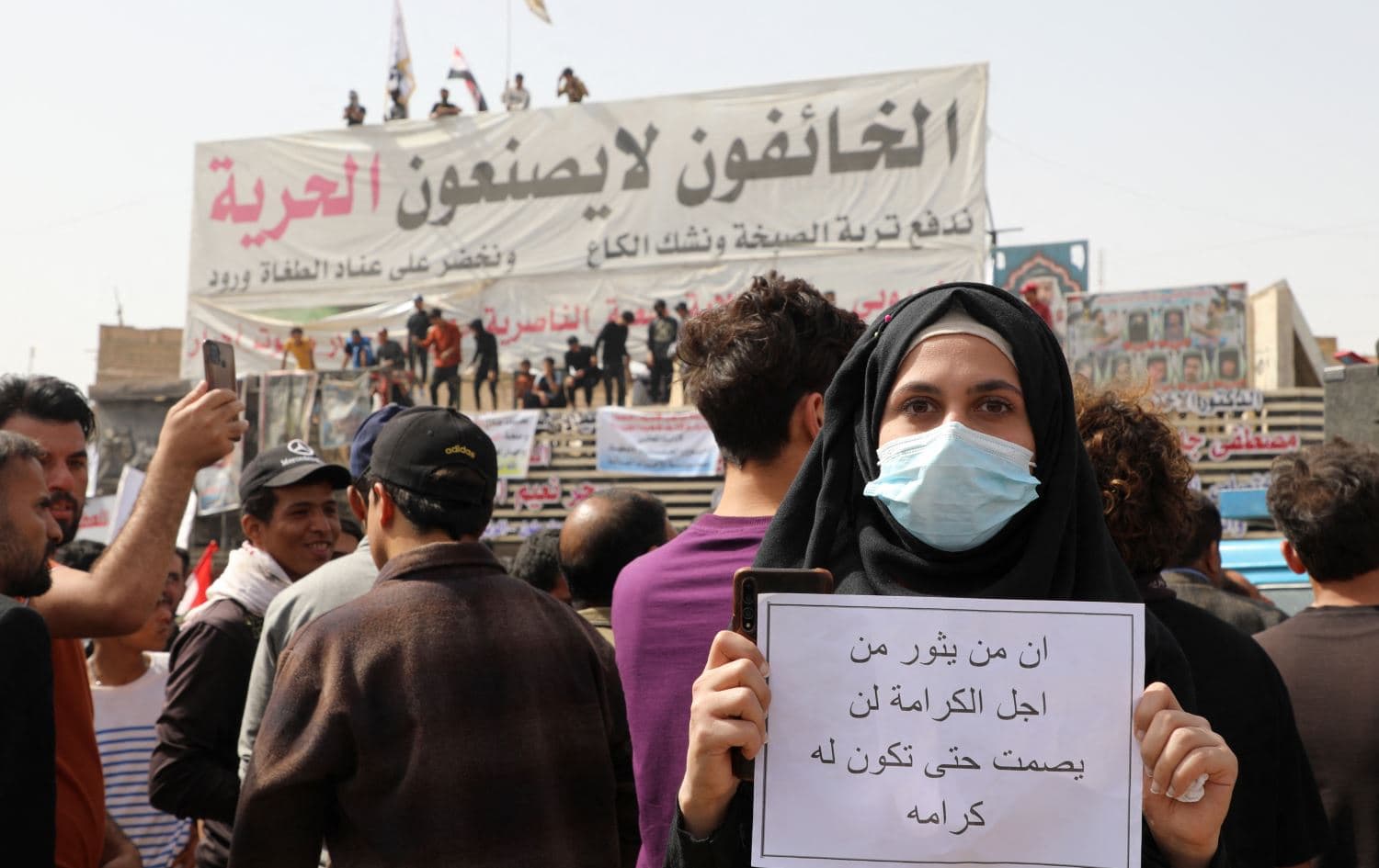 An Iraqi carries a placard which reads in Arabic "Then you revolt for pride, you won't stop until you achieve your goal" during a demonstration to denounce rising prices of basic food items in Nasiriyah on March 9, 2022.