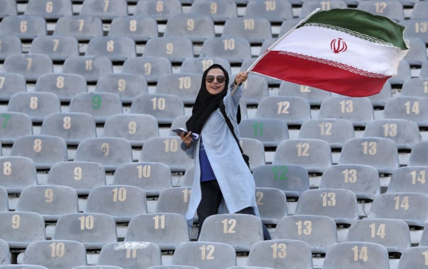 An Iranian woman waves her country’s flag at a football game in Tehran, Iran, on October 10, 2019. Photo: Vahid Salemi/AP