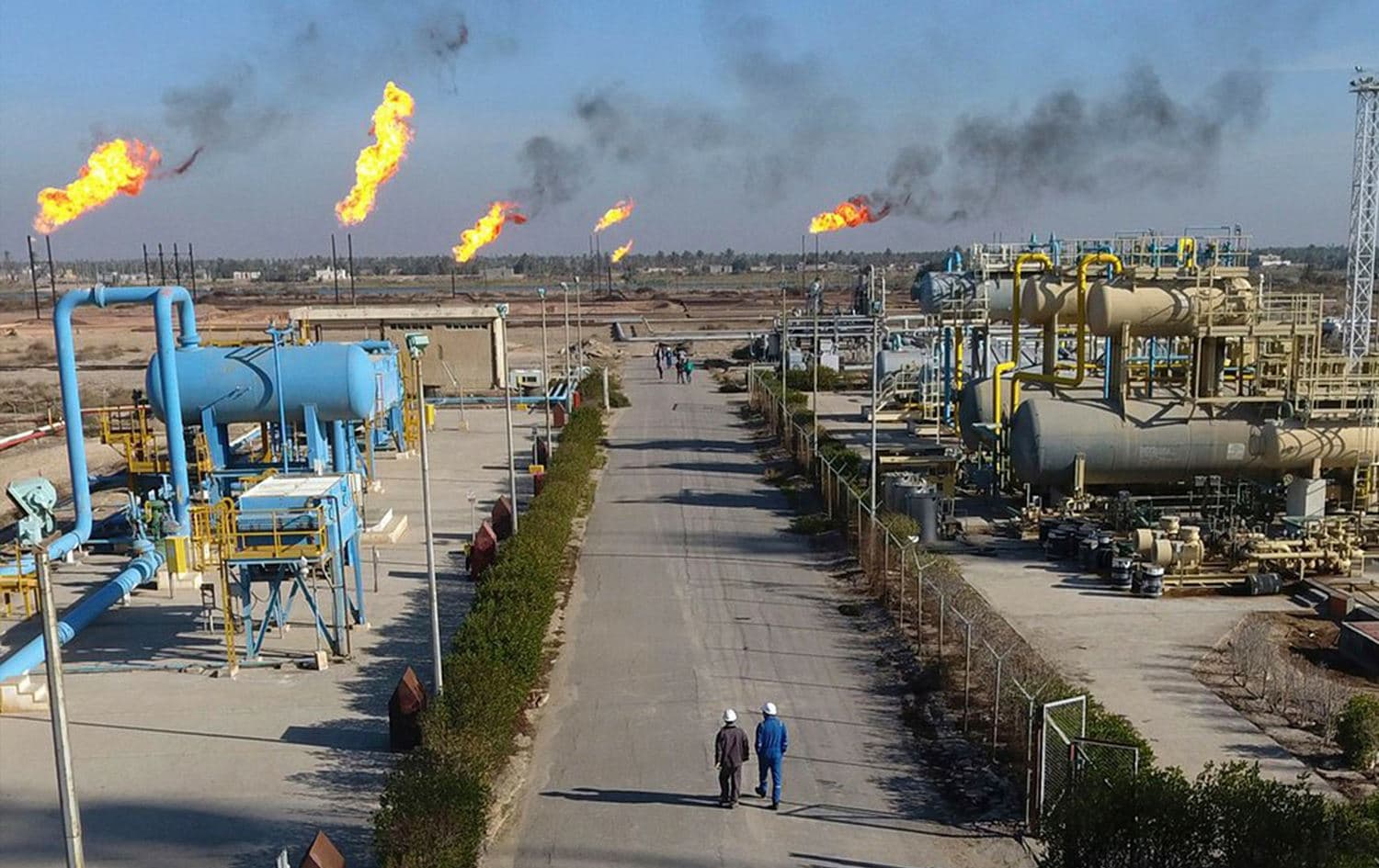 Workers walk down a path in the Nihran Bin Omar oil field north of Basra, Iraq on January 12, 2022. Photo: Nabil al-Jurani/AP