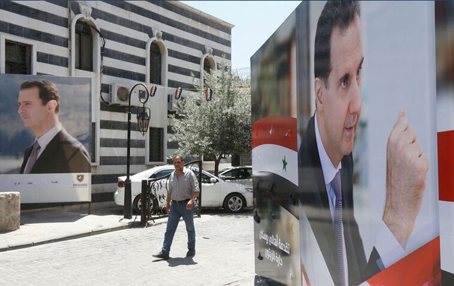 A Syrian man walks walks in between election campaign posters bearing portraits of Syrian President Bashar al-Assad in the capital Damascus on May 18, 2021. Photo: AFP