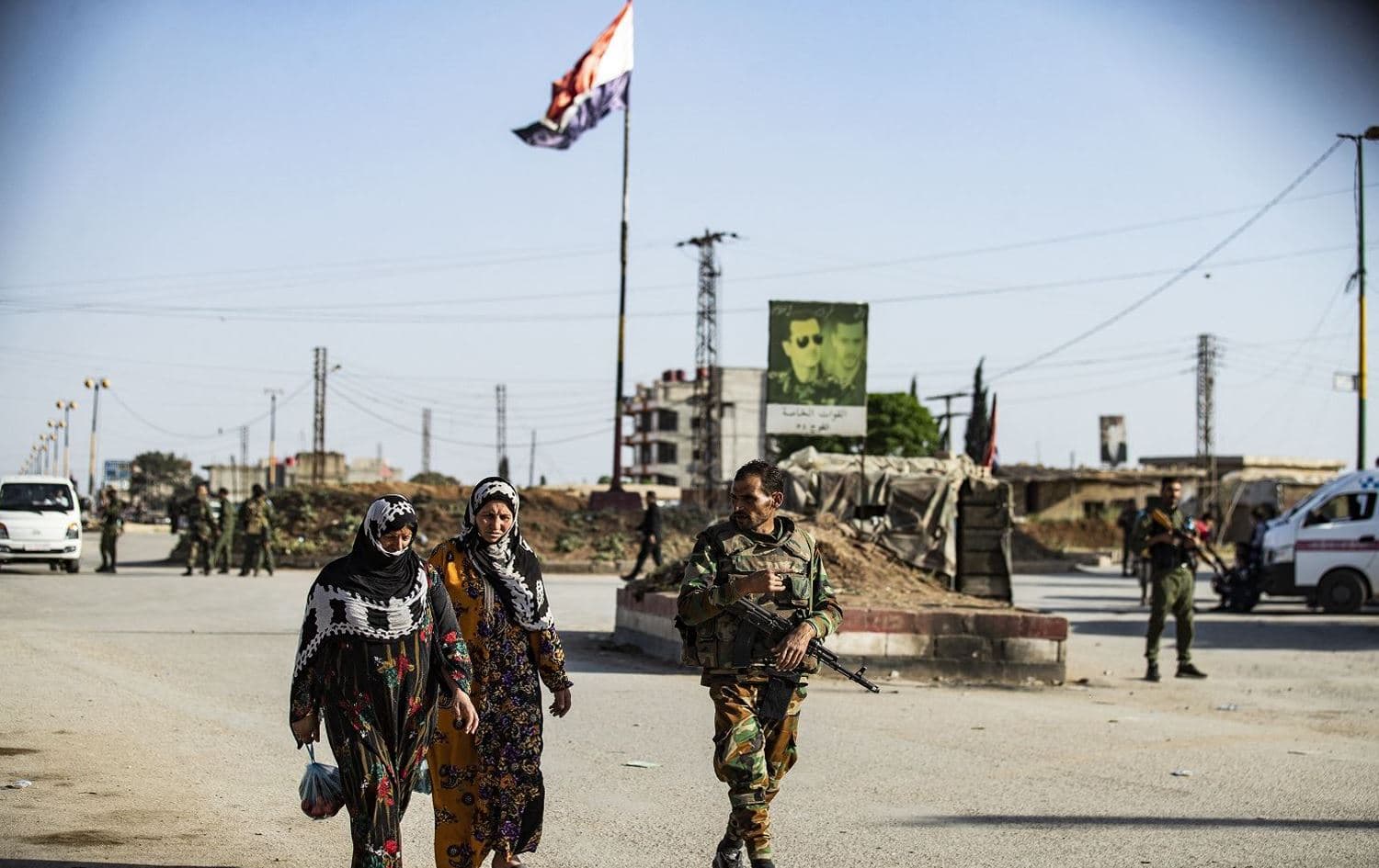 A member of Syrian government forces escorts women at a joint checkpoint with the Kurdish local forces (Asayish) in Qamishli's al-Tai neighbourhood on April 27, 2021. Photo: Delil Souleiman/AFP.