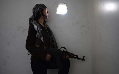 A woman member of the Kurdish Peoples Protection Units (YPG) takes position inside a ruined house in Aleppo amid clashes with Syrian regime forces. Photo: AFP