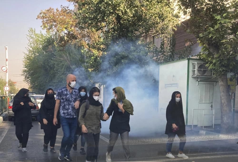 In this Oct. 1, 2022 photo taken by an individual not employed by the Associated Press and obtained by the AP outside Iran, tear gas is fired by security to disperse protestors in front of the Tehran University, Iran.