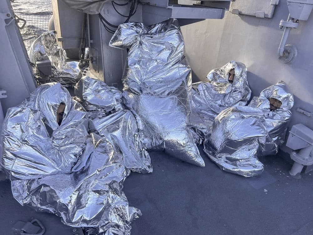 In this photo provided by the Greek Coast Guard, some of the nine men who survived a shipwreck and were found on an uninhabited islet are covered with a thermal blankets as they sit aboard a Greek Coast guard vessel, in the Aegean Sea, Greece, on November 1, 2022.