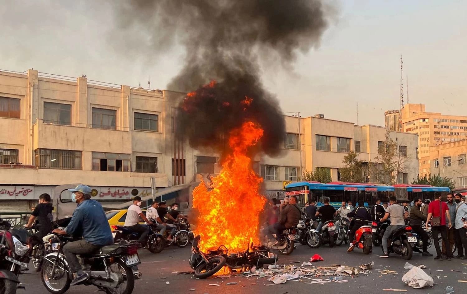 A picture obtained by AFP outside Iran shows people gathering next to a burning motorcycle in the capital, Tehran, on October 8, 2022. Photo: AFP