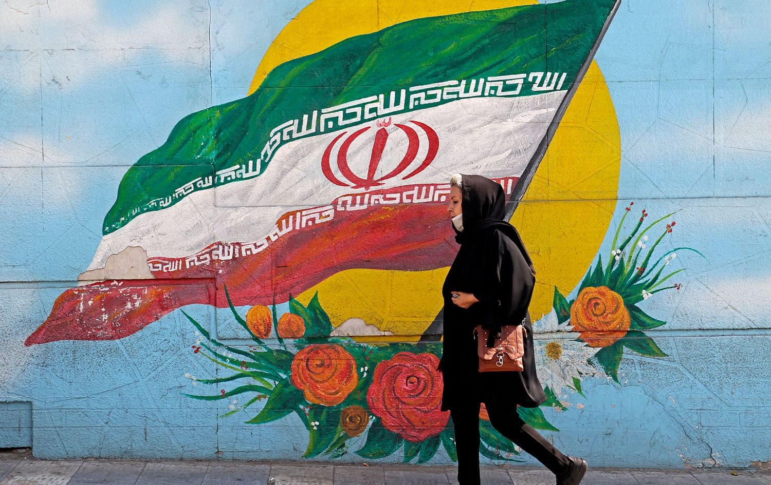 Woman walking past a mural in Tehran on October 11, 2022. Photo: Atta Kenare/AFP
