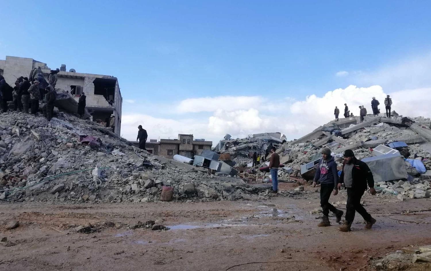 People walk past collapsed buildings in Jindires, northern Syria on February 9, 2023 following Monday's devastating earthquake. Photo: Rezan Hiske/Rudaw