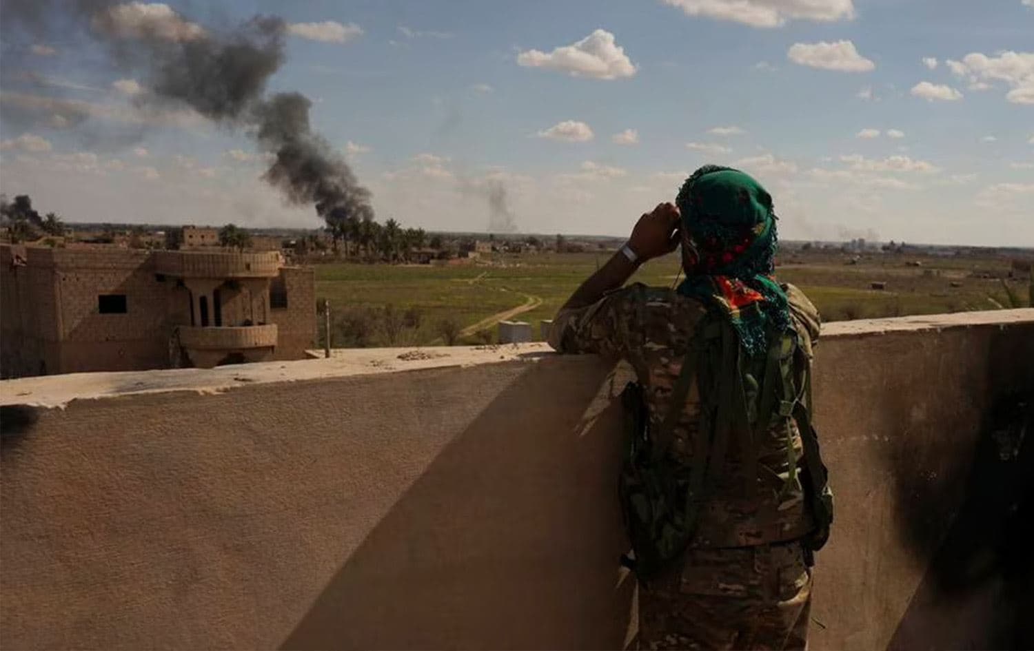 A U.S.-backed Syrian Democratic Forces (SDF) fighter watches black smoke billow from the last small piece of territory held by Islamic State militants as U.S. backed fighters pounded the area with artillery fire and occasional airstrikes in Baghouz, Syria, Sunday, March 3, 2019. Photo: Andrea Rosa/AP