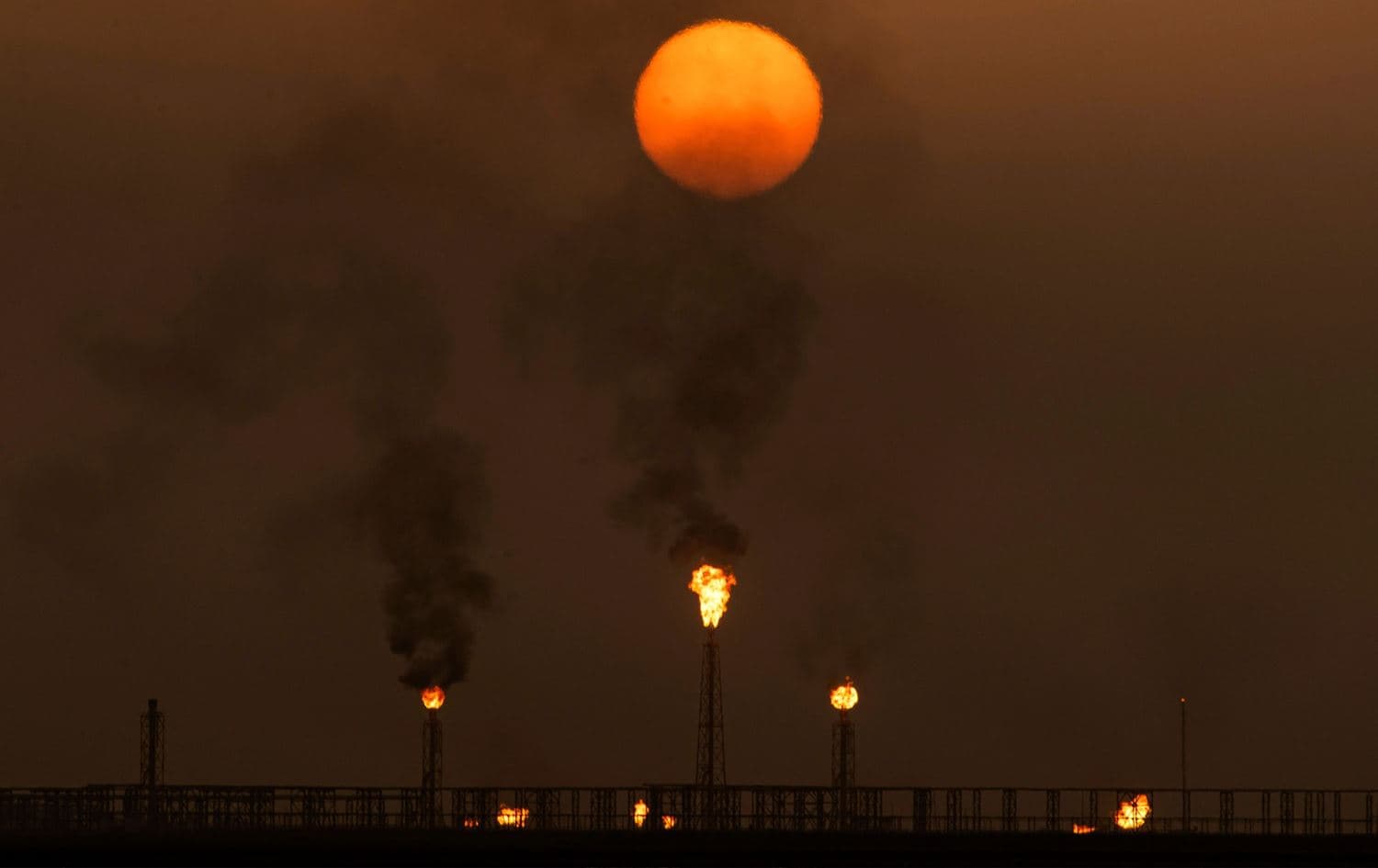 The sun sets as flare stacks burn off excess gas at the Mushrif site inside the Zubair oil and gas field, north of the southern Iraqi province of Basra, on July 13, 2022. Photo: Hussein Faleh/AFP