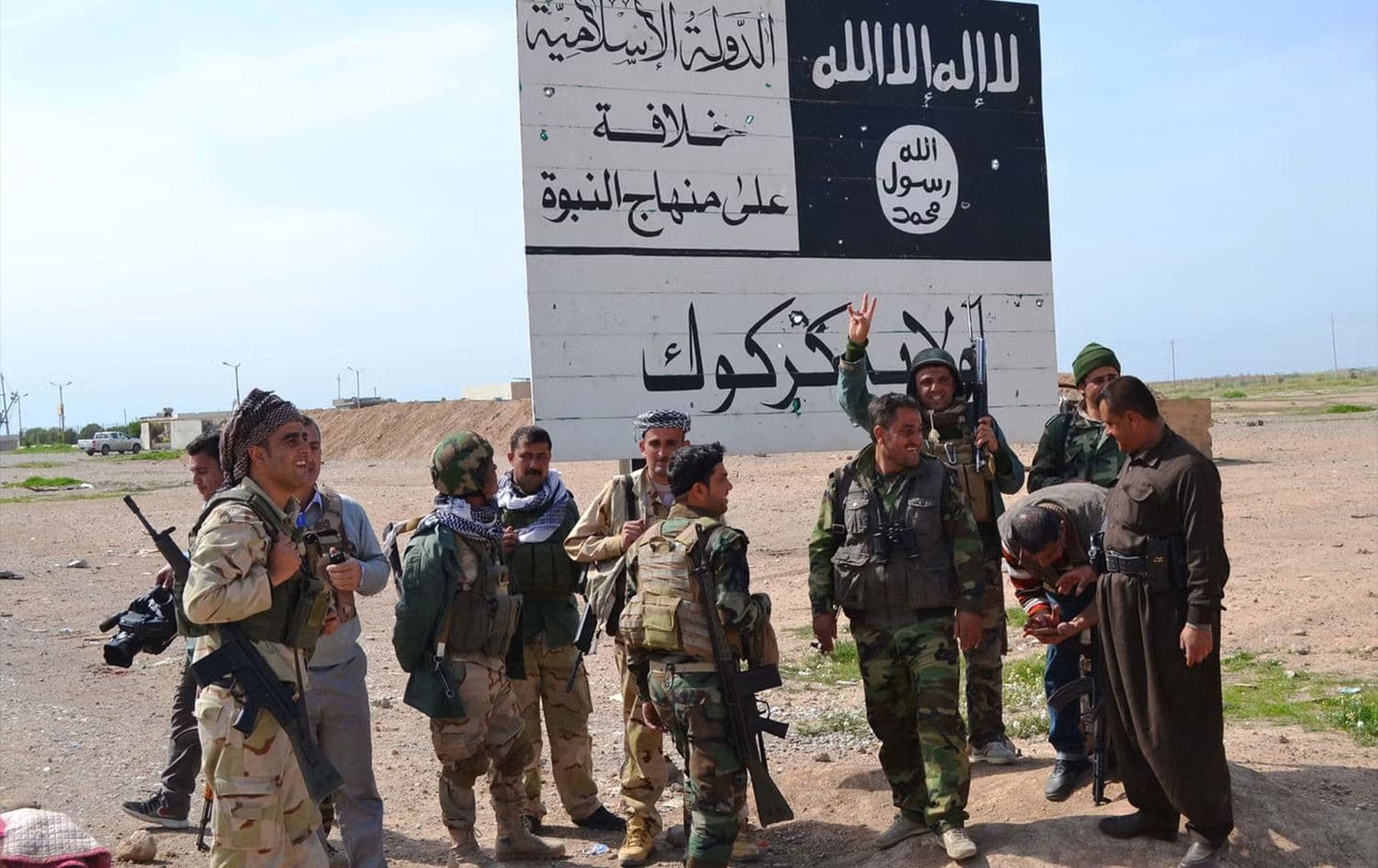 Kurdish Peshmerga fighters next to an ISIS sign at the entrance to the northern Iraqi town of Hawija, south of Kirkuk, in March 2015. Photo: AFP
