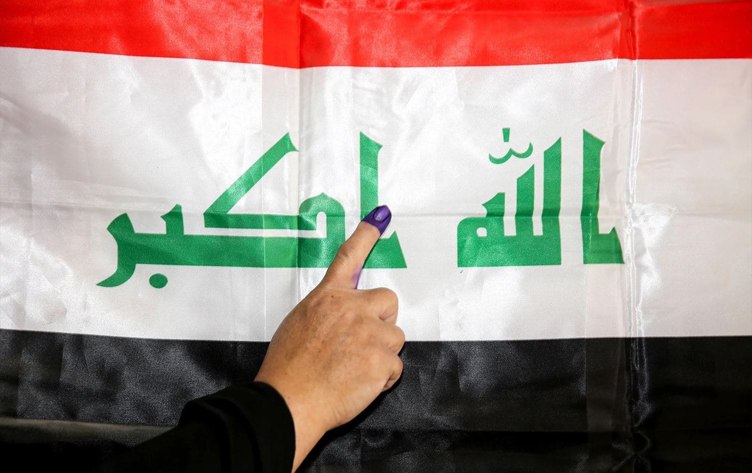 An Iraqi woman shows her ink-stained index finger before a national flag after having cast her vote in the country’s 2018 parliamentary election, in the Karrada district of Baghdad. File photo: AFP