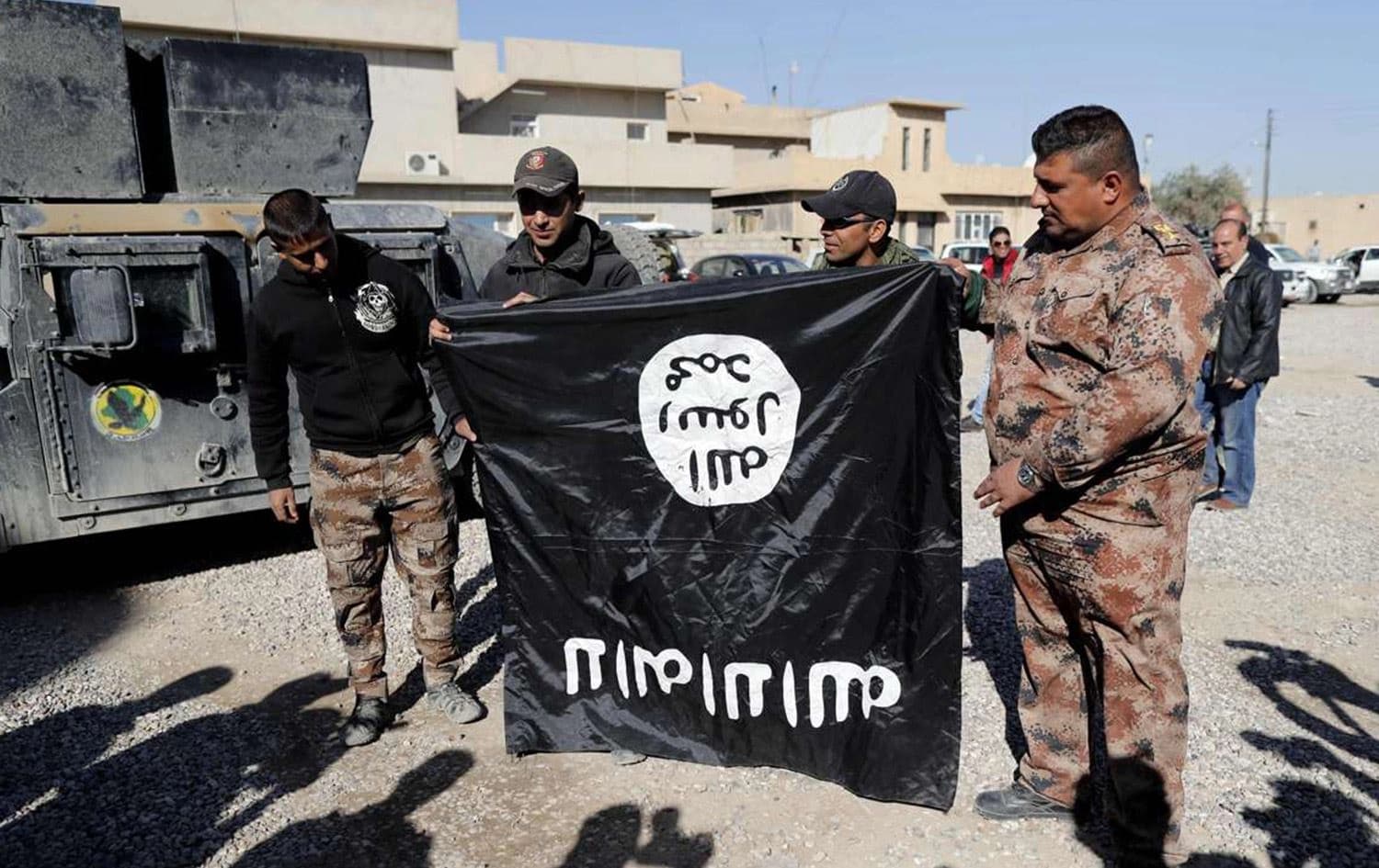 Iraqi army soldiers hold a captured flag from the Islamic State (IS) jihadist group upside-down on Wednesday, near an Iraqi army base in the outskirts of Mosul. Photo: AFP