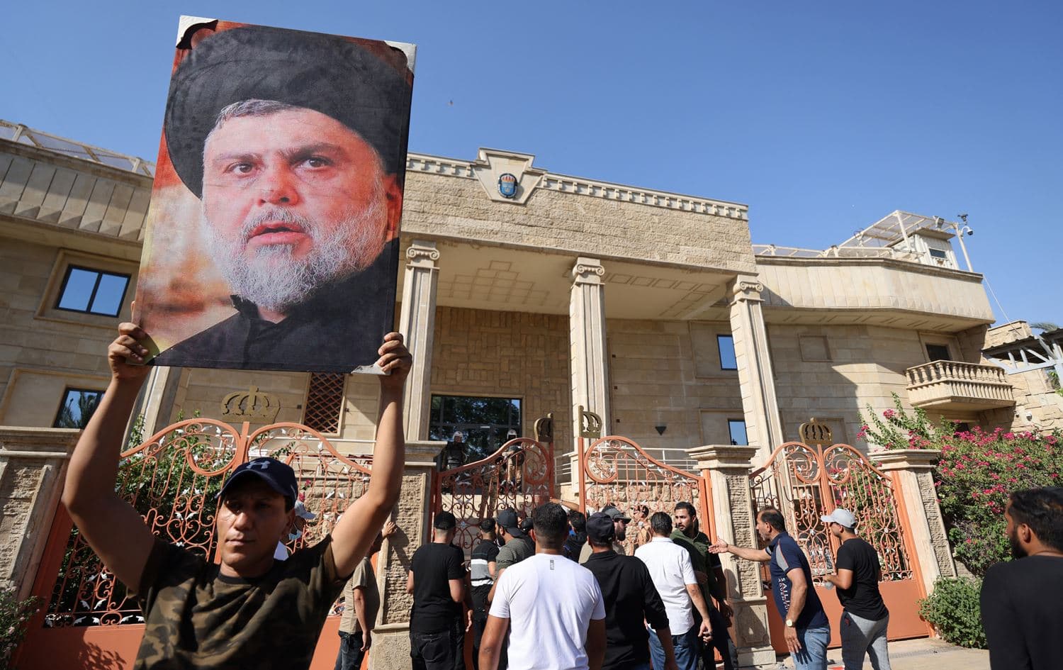 A Muqtada al-Sadr supporter raises a picture of the Shiite leader, as others demonstrate inside the courtyard of the Swedish embassy in Baghdad after they breached the building briefly over the burning of the Quran by an Iraqi living in Sweden, on June 29, 2023. Photo: Ahmad al-Ruabye / AFP