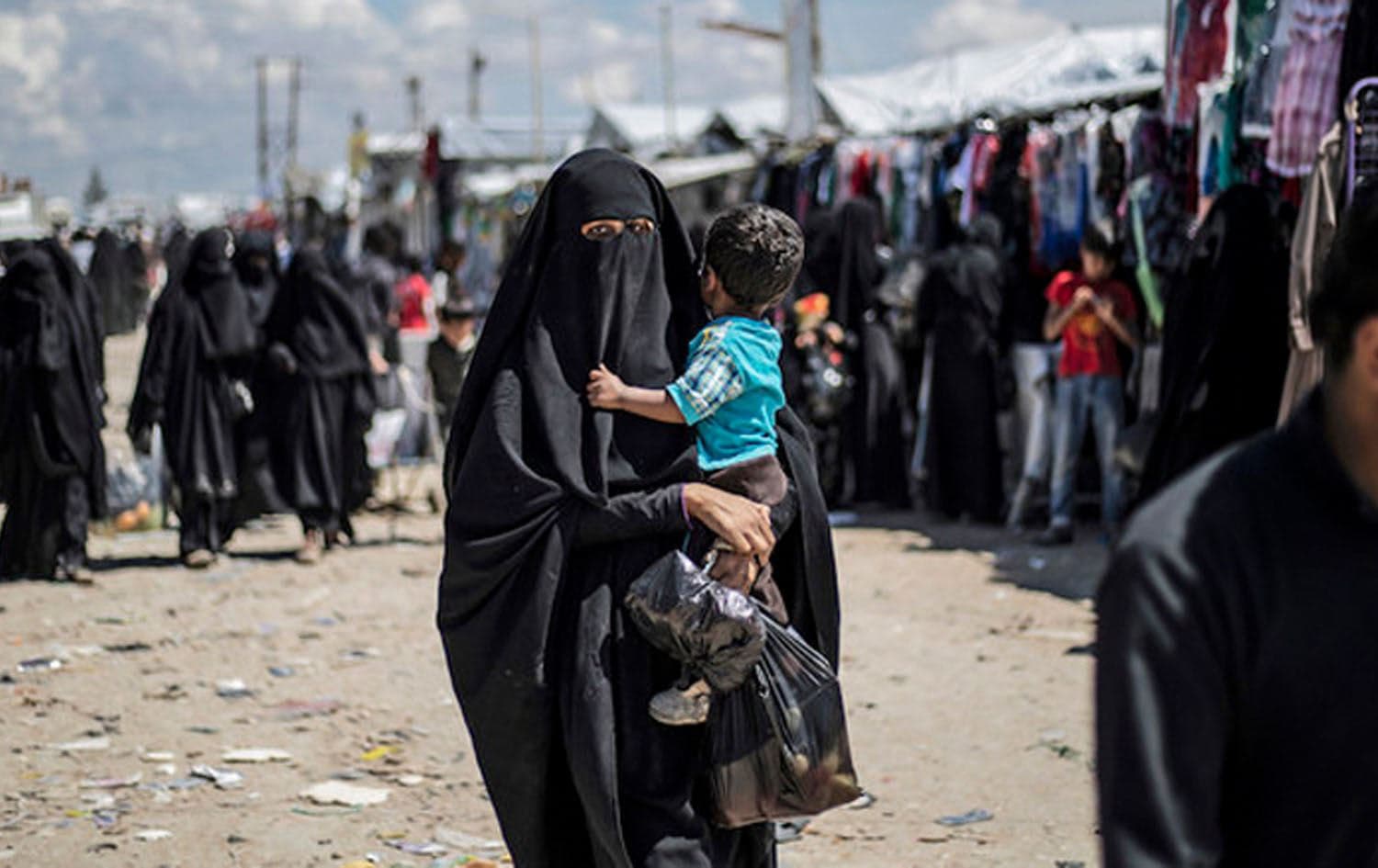 A veiled woman carries a toddler in northeast Syria's Al-Hol Camp. Photo: Delil Souleiman/AFP