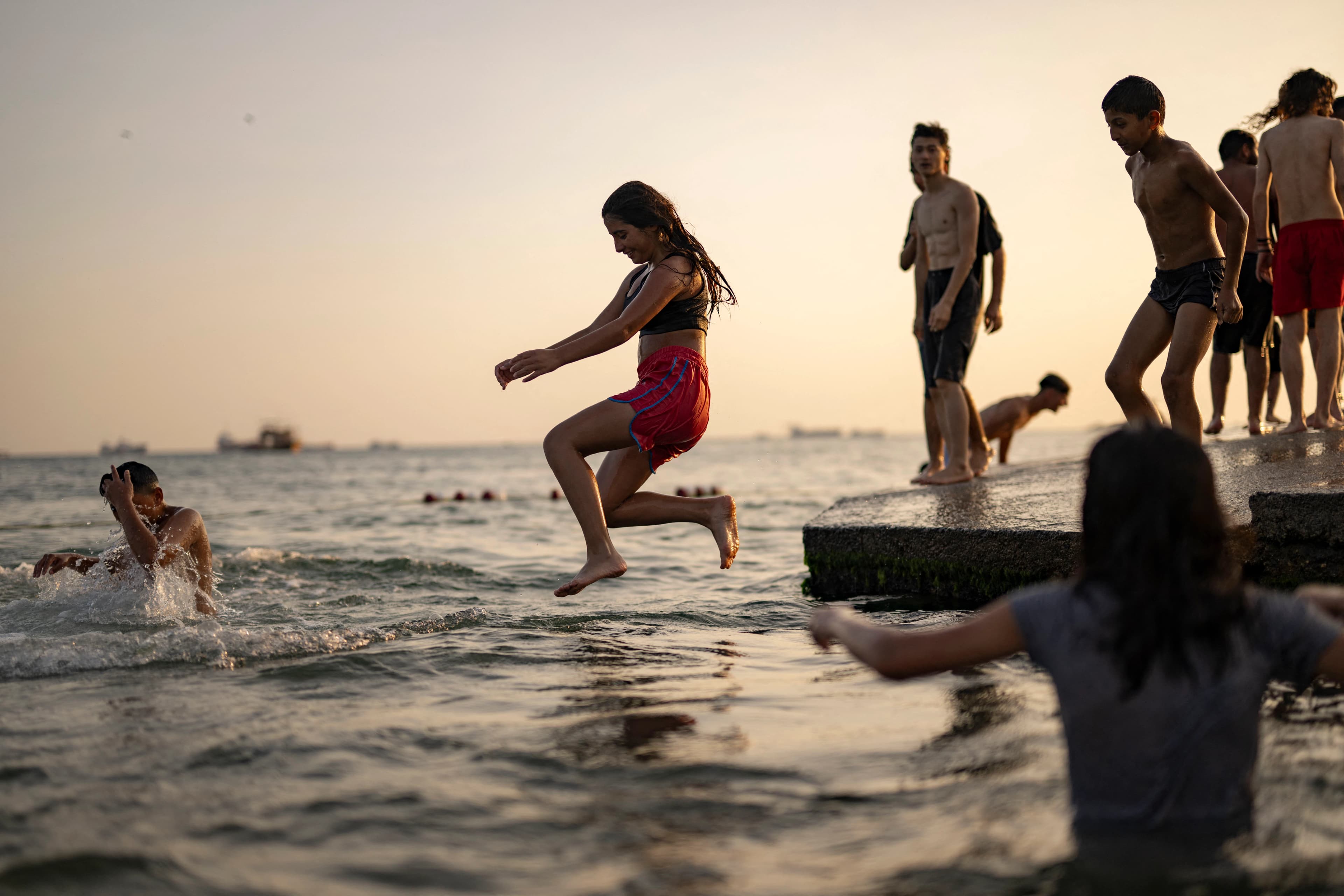 A girl in shorts and t-shirt jumps into the sea at Menekse beach in Istanbul on July 23, 2023. Photo: AFP 