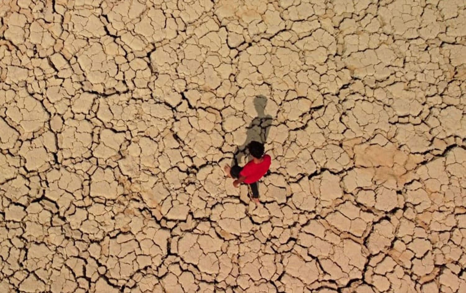 A young man walks on cracked and dried-up soil at the Hawizeh marshes, which straddle Iraq's border with Iran, in October 2022. Photo: AFP