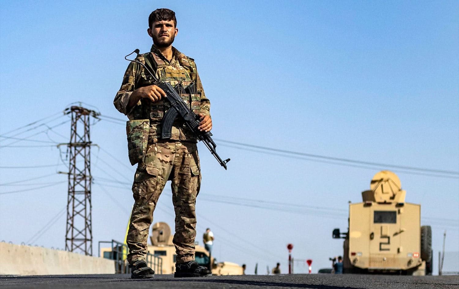A fighter of the Syrian Democratic Forces (SDF) stands guard along a road as others deploy to impose a curfew in the town of al-Busayrah in Syria's northeastern Deir Ezzor province on September 4, 2023, during a guided media tour organised by the SDF. Photo: Delil Souleiman/AFP