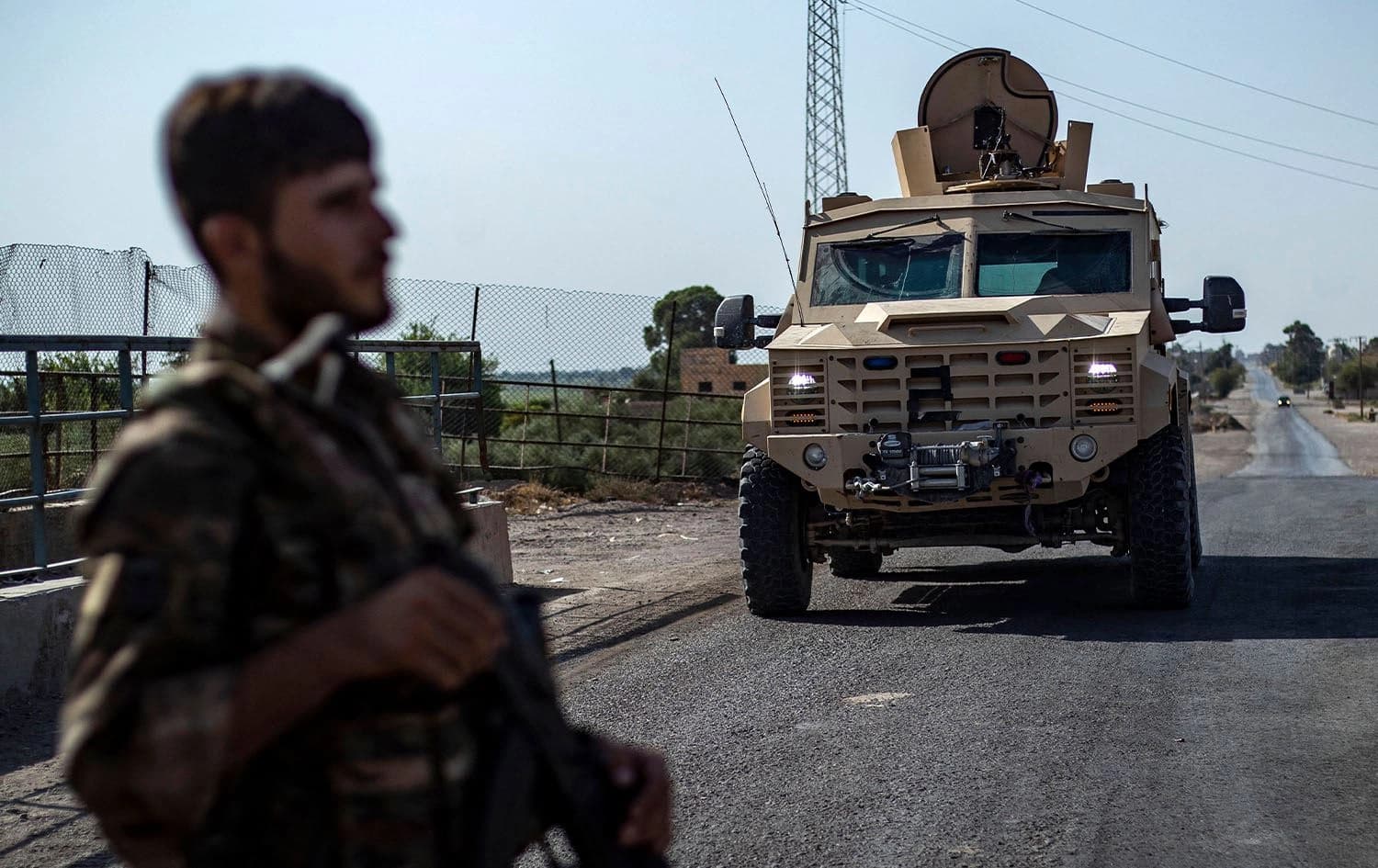 A fighter of the Syrian Democratic Forces (SDF) stands guard along a road as others deploy to impose a curfew in the town of al-Busayrah in Syria's Deir ez-Zor province on September 4, 2023. Photo: Delil Souleiman/AFP