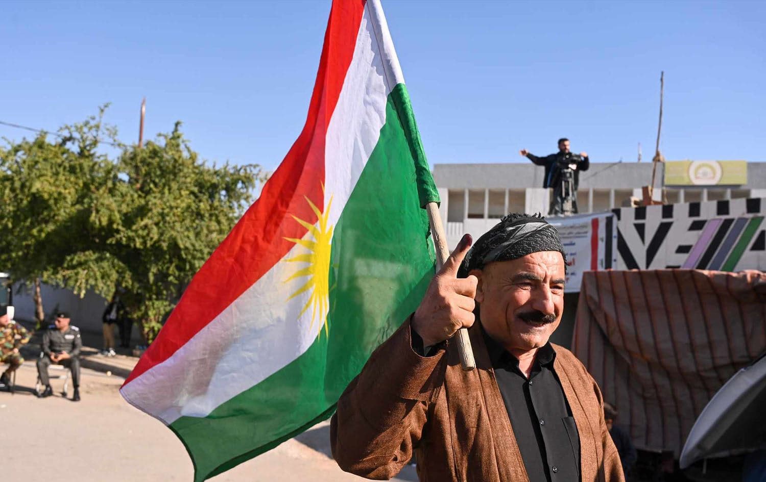 A Kurdish man wearing traditional Kurdish clothes and waving the flag of Kurdistan while showing off his index finger marked with indelible ink signifying that he cast his vote in Iraq's provincial election on December 18, 2023. Photo: Bilind T. Abdullah/Rudaw