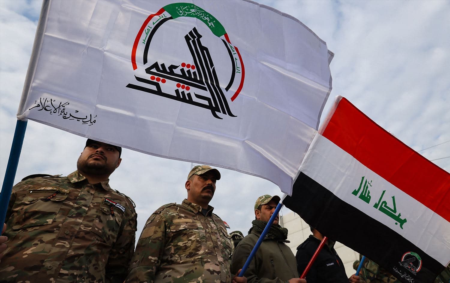 Members of Iraq's Hashed al-Shaabi (Popular Mobilisation) paramilitary forces, carry their flag as well as that of Iraq, ahead of the funeral of people killed the previous day in US strikes in western Iraq, in Baghdad on January 4, 2024. Photo: Ahmed al-Rubaye/AFP