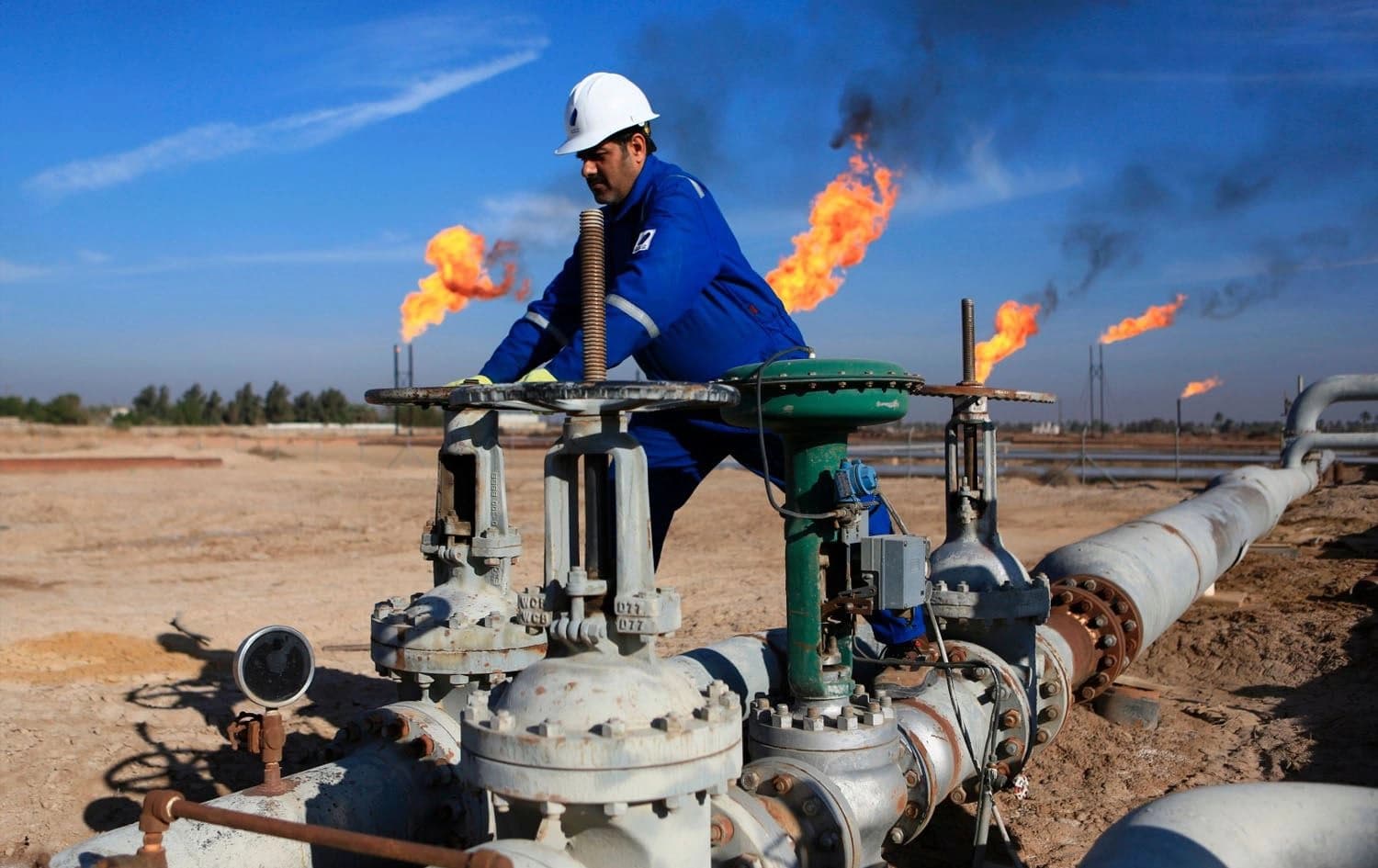 An Iraqi worker operates valves in Nihran Bin Omar field north of Basra, Iraq. Photo: AP