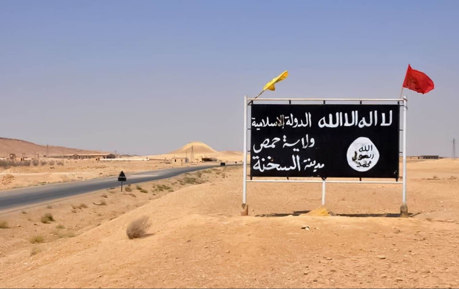 An ISIS poster in the central Syrian town of Sukhnah is adorned with the flags of pro-government fighters after the Syrian government took control of the area. File photo: AFP