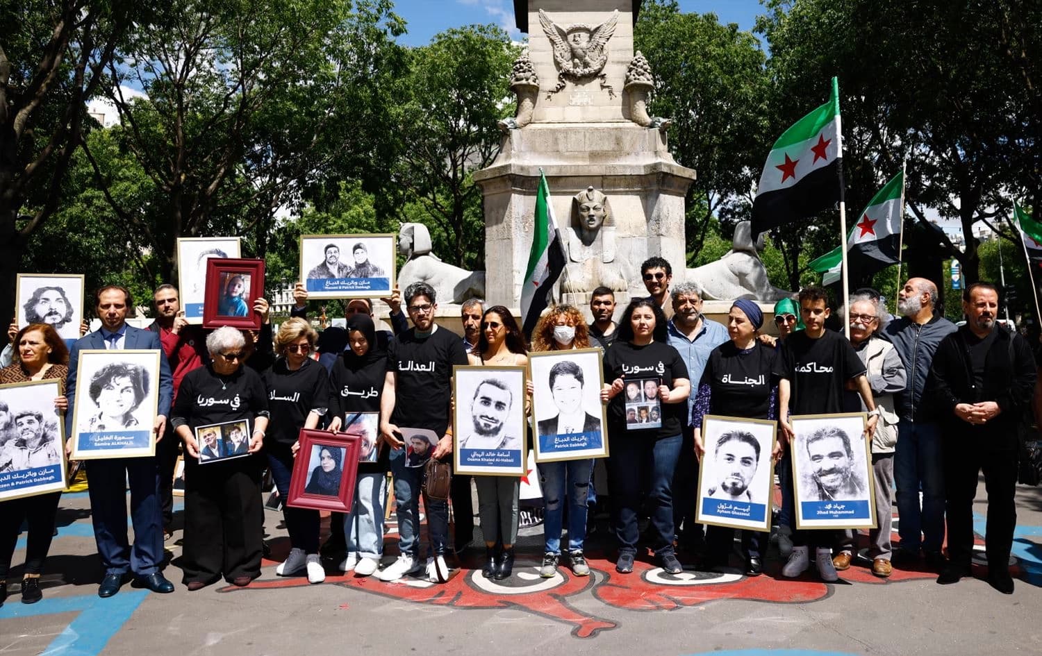 کەسوکاری قوربانییانی جەنگی سووریا لەکاتی دادگاییکردنەکە، لە دەرەوەی دادگەکە خۆپێشاندان دەکەن. 