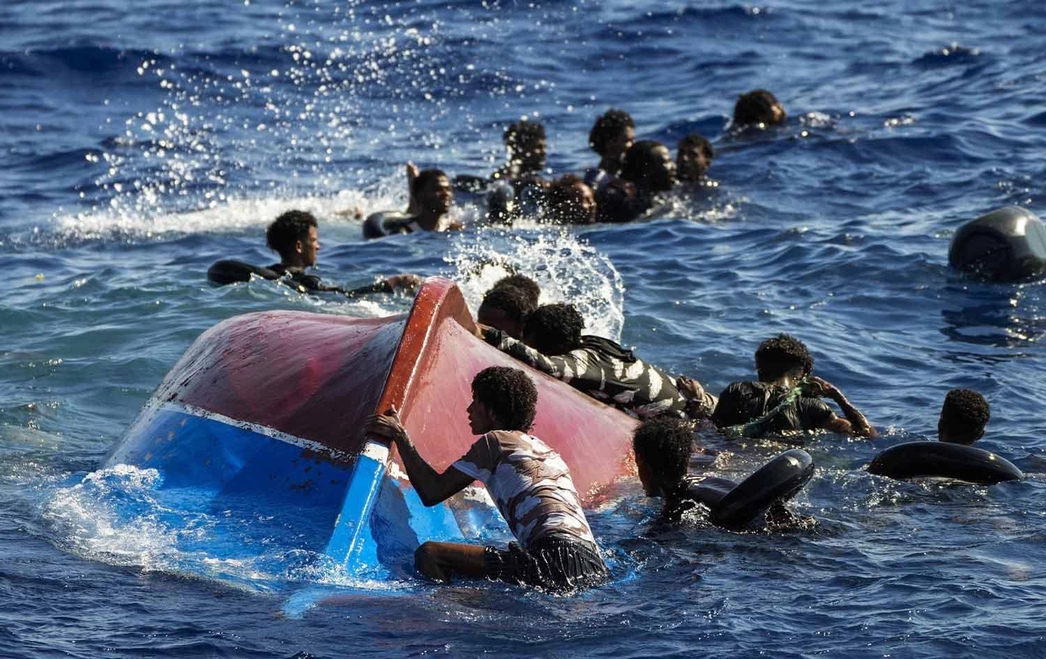 Migrants swim next to their overturned wooden boat during a rescue operation by Spanish NGO Open Arms south of the Italian Lampedusa island in the Mediterranean Sea on August 11, 2022. Photo: AP