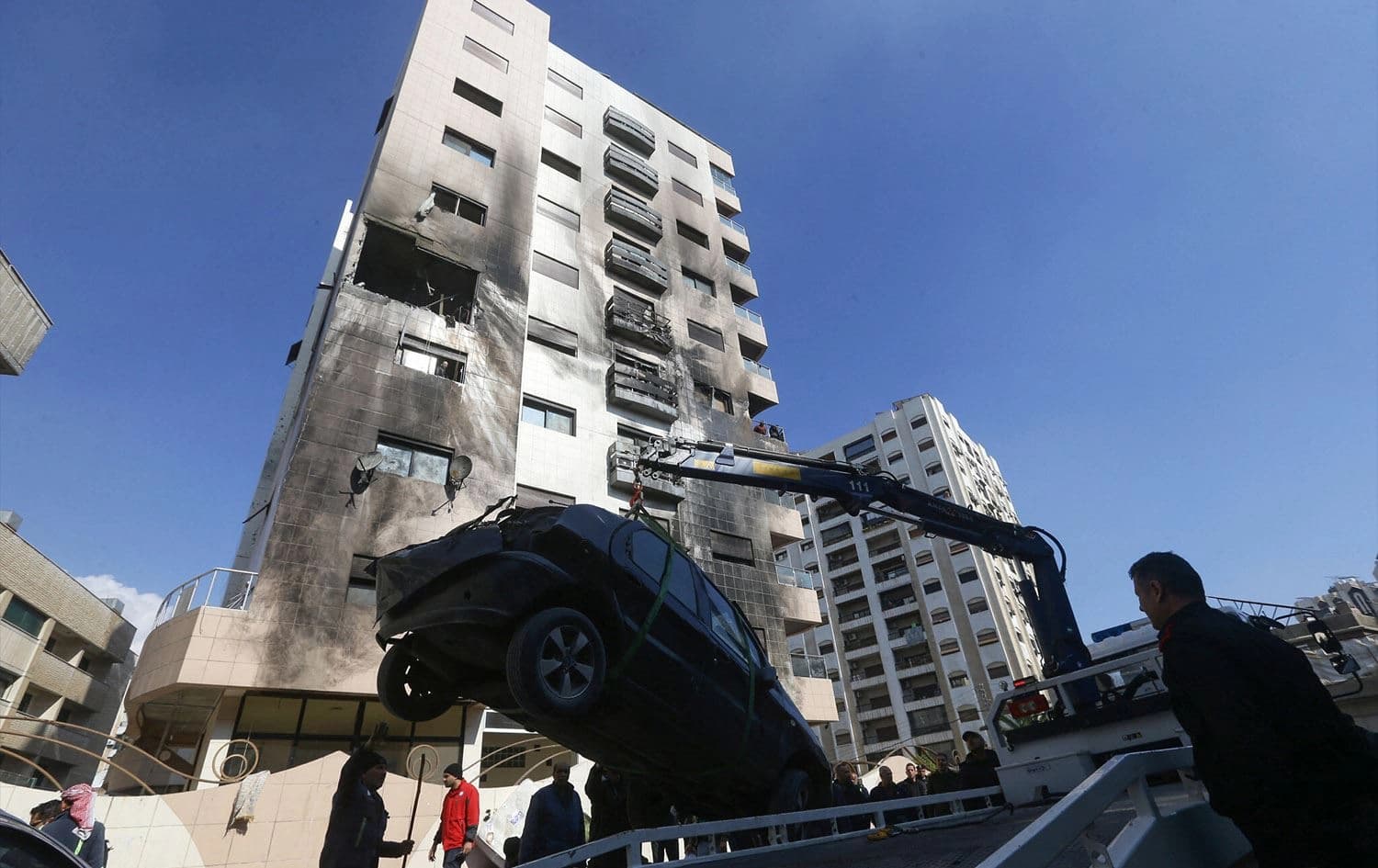 A car is removed from the area where reported Israeli air strikes targeted a residential building in the Kafr Sousa district of the Syrian capital Damascus on February 21, 2024. Photo: Louai Beshara/AFP