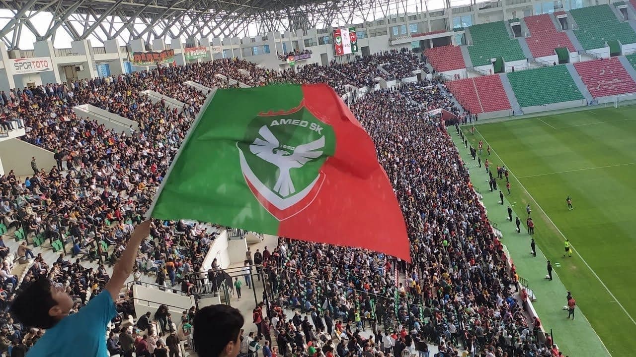 هاندەرێکی یانەی ئامەد سپۆر بە ئاڵای یانەکەوە لەنێو یاریگە