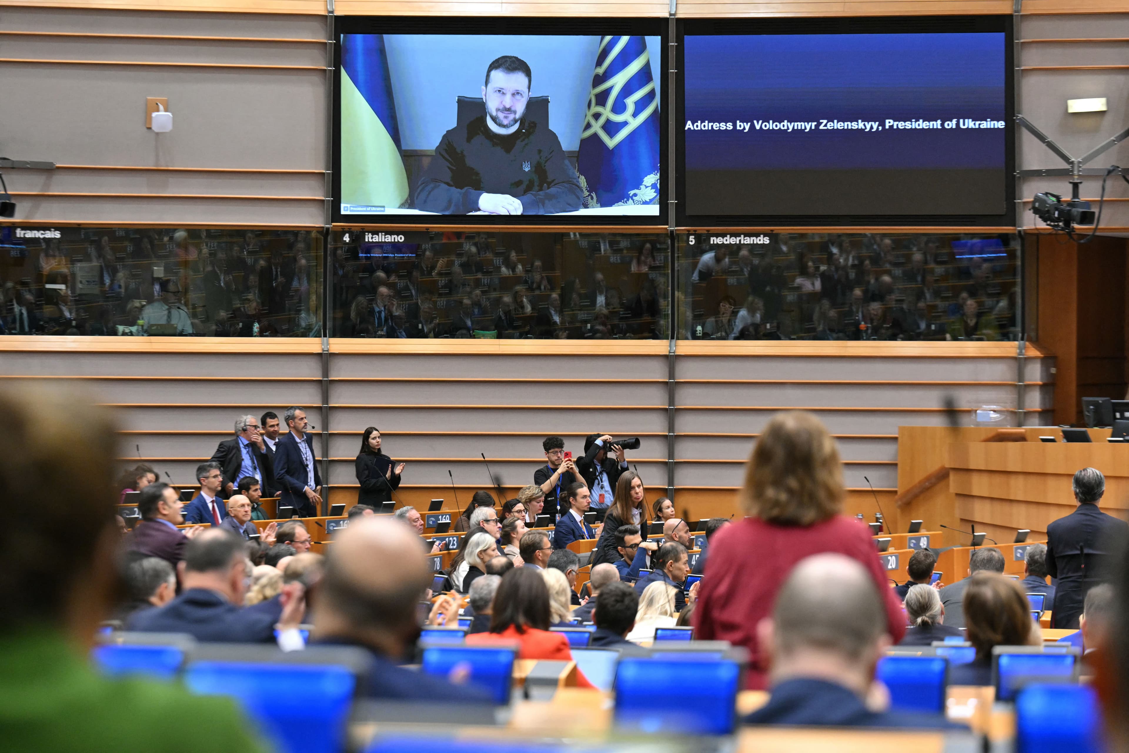 Members of the EU parliament clap at the end of a videoconference speech by Ukraine's President Volodymyr Zelensky (screen) at the EU Parliament in Brussels on November 19, 2024. Photo: AFP