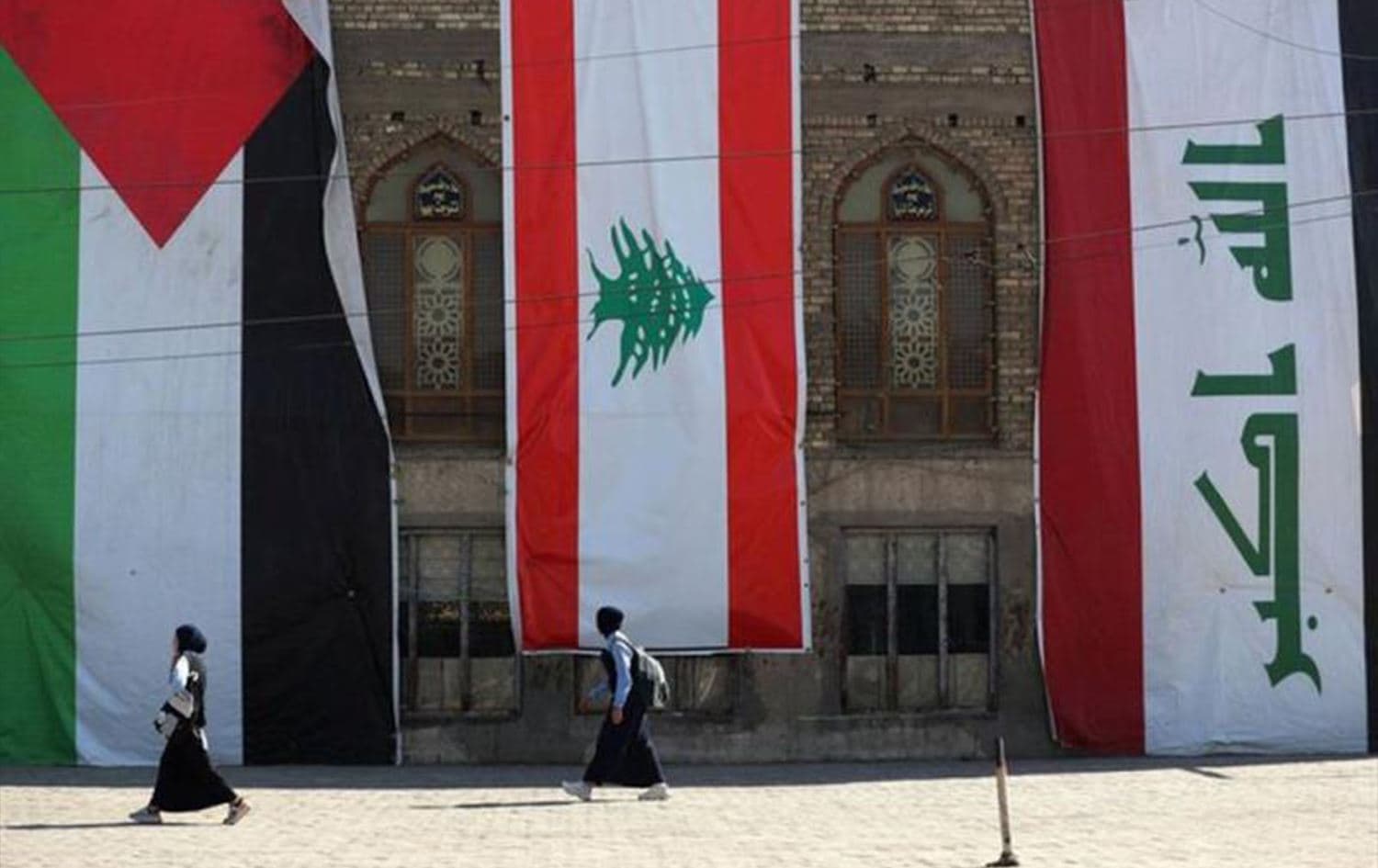 Iraqi students walk past the flags of Palestine, Lebanon and Iraq, hanging on the side of a mosque in the capital Baghdad on October 27, 2024. Photo: Ahmad al-Rubaye/AFP