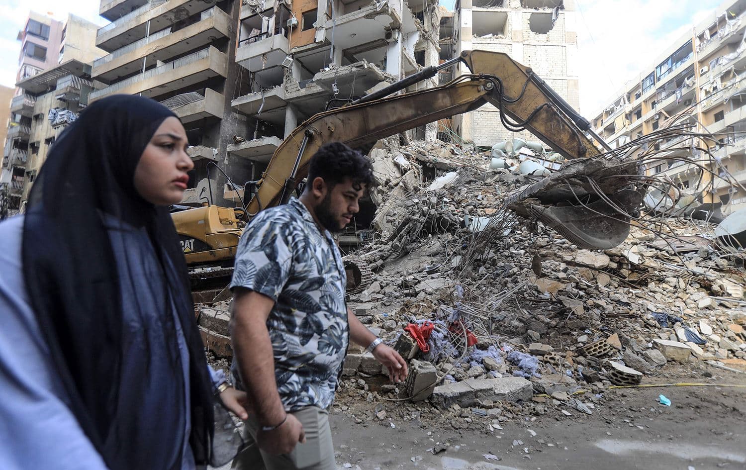 Lebanese people walking past the rubble of buildings destroyed by Israeli strikes. Photo: AFP