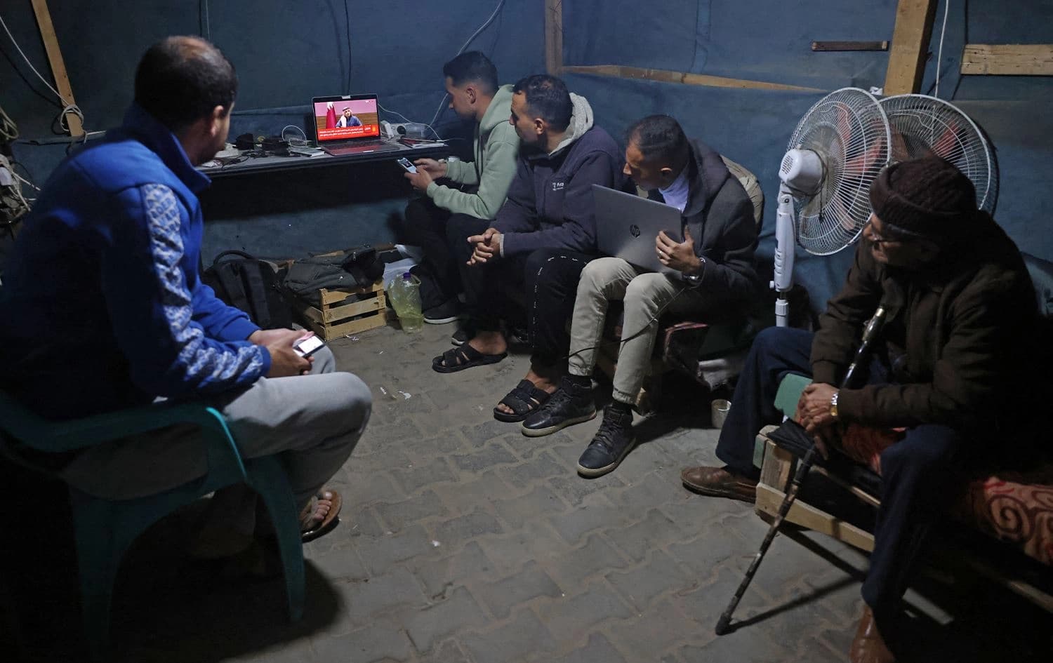 People watch the live broadcast of a press conference being addressed by Qatar’s prime minister inside a tent in Khan Yunis in the Gaza Strip on January 15, 2025. Photo: Bashar Taleb/AFP