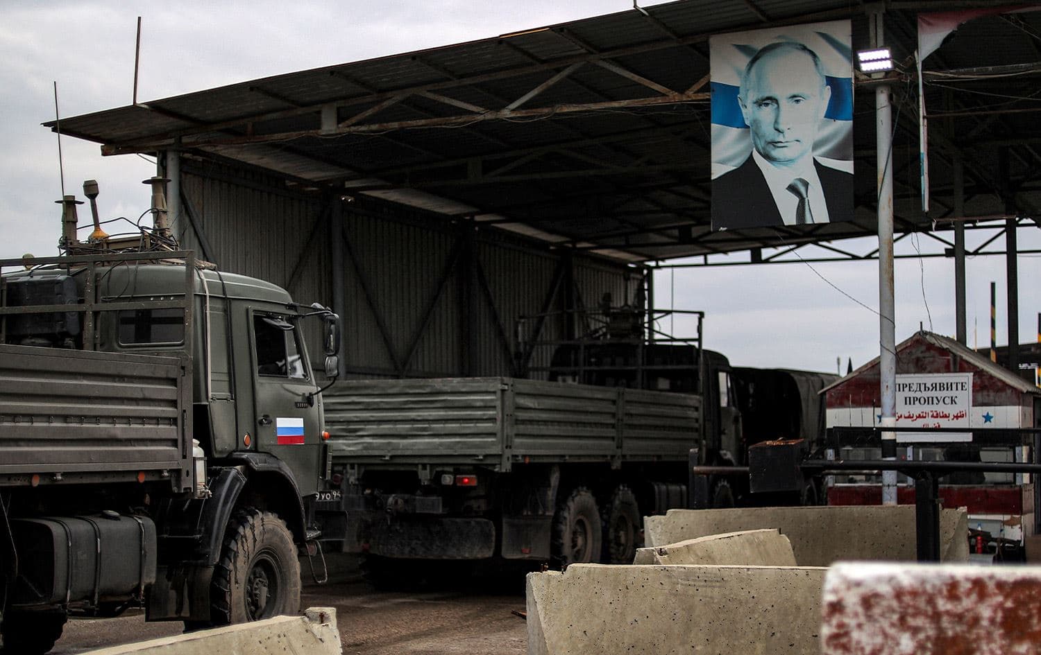 A portrait of Russia's President Vladimir Putin hangs above as Russian military trucks enter the Russian-leased Syrian military base of Hmeimim in Latakia province in western Syria on December 29, 2024. Photo: Aaref Watad/AFP