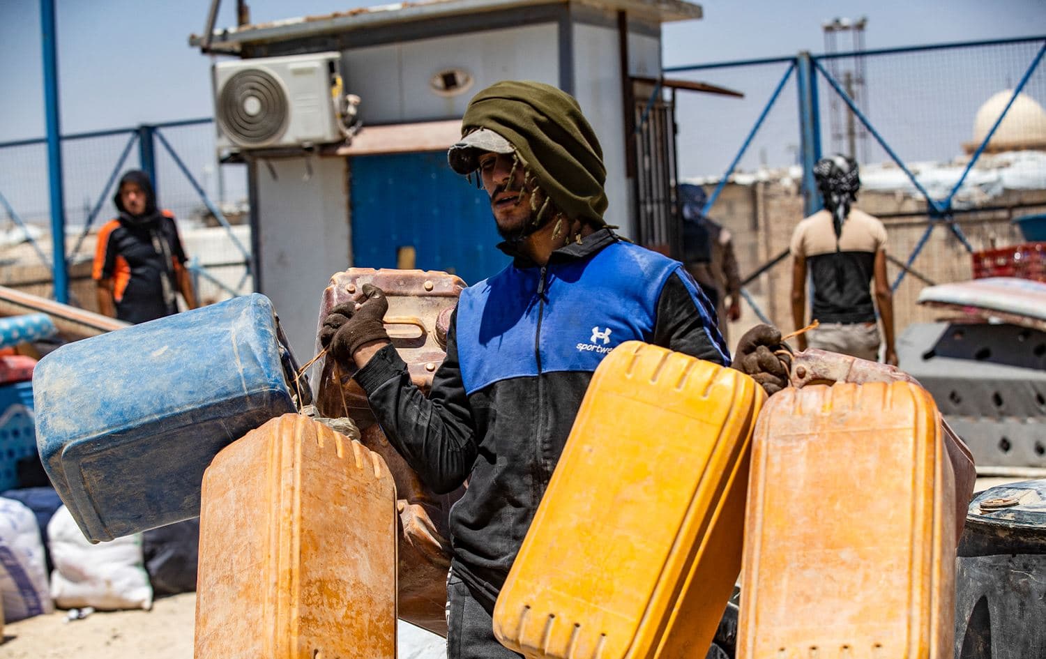 A man carries plastic containers at al-Hol camp in the northeastern Al-Hasakah Governorate on July 28, 2024, as families of suspected Islamic State fighters prepare to return to their homes in the countryside of Deir ez-Zor. Photo: Delil Souleiman/AFP