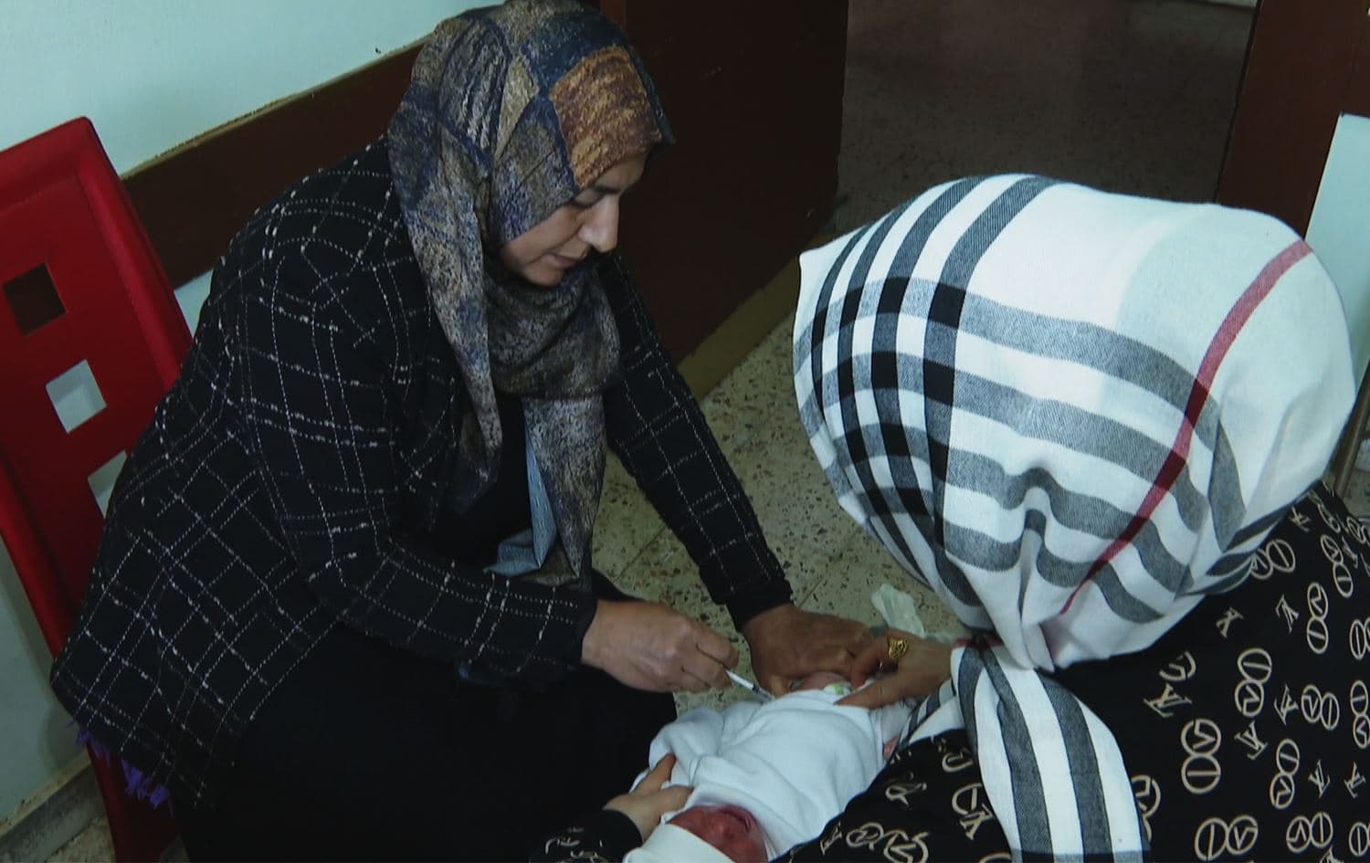 کارمەندێکی تەندروستی کوتان بۆ منداڵێک دەکات. وێنە: رووداو