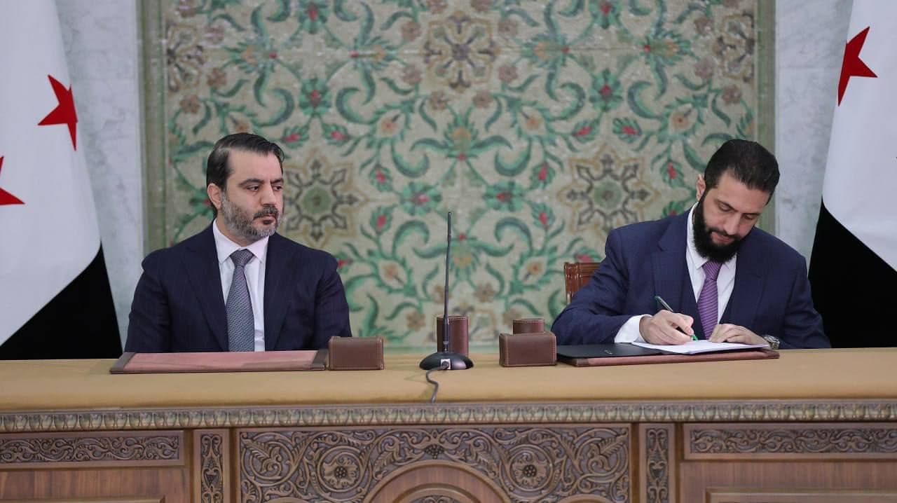Syrian interim President Ahmed al-Sharaa (right) signs constitutional declaration in Damascus on March 13, 2025. Photo: Syrian presidency