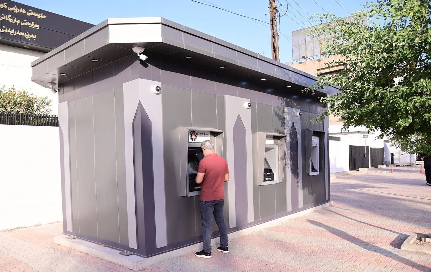 A person at a bank and the logo of the Kurdistan Regional Government's 'My Account' initiative. Photo: Rudaw