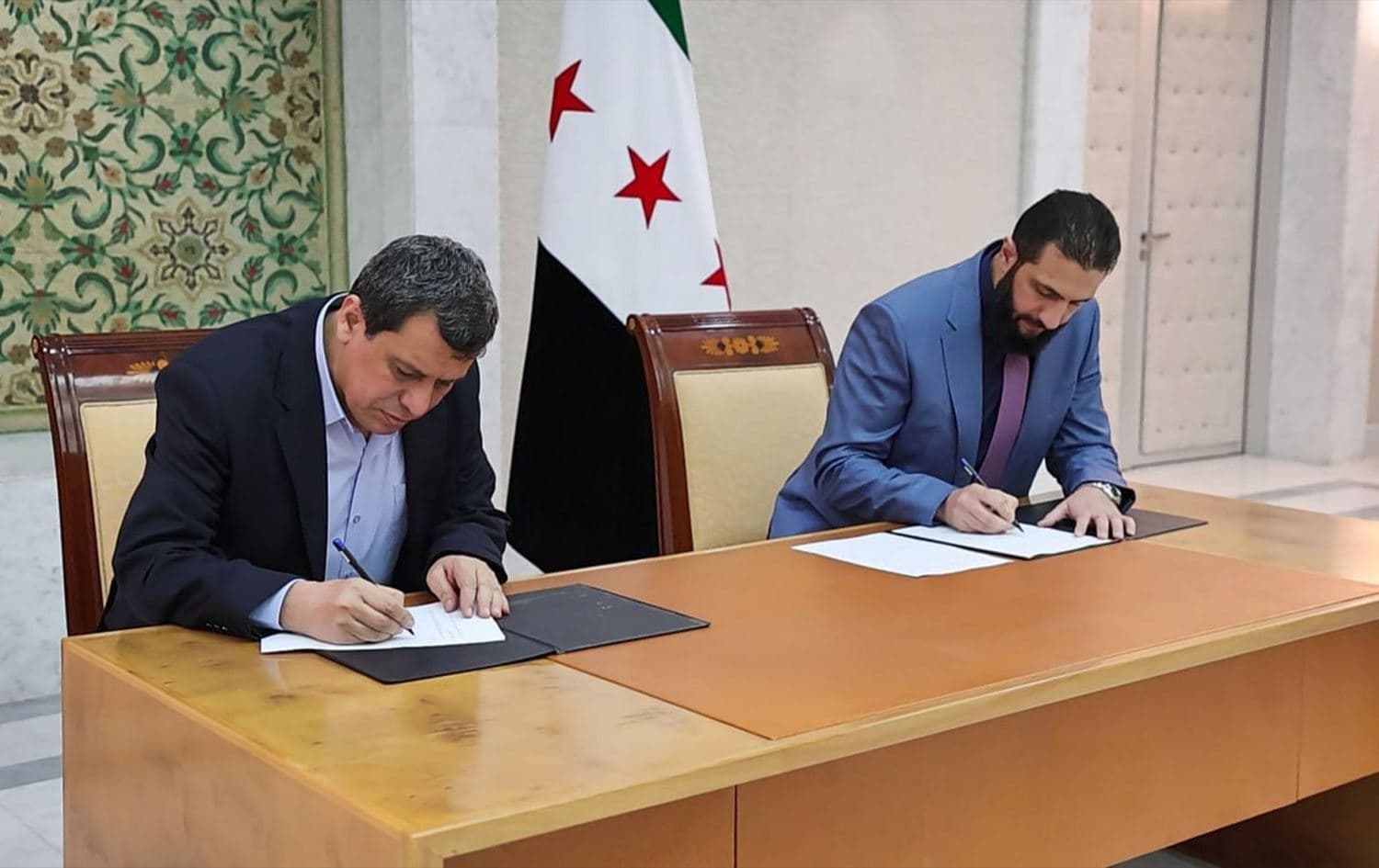 Syrian interim President Ahmed al-Sharaa (right) and Syrian Democratic Forces (SDF) chief Mazloum Abdi (left) signing a deal on March 10, 2025. Photo: Sharaa’s office