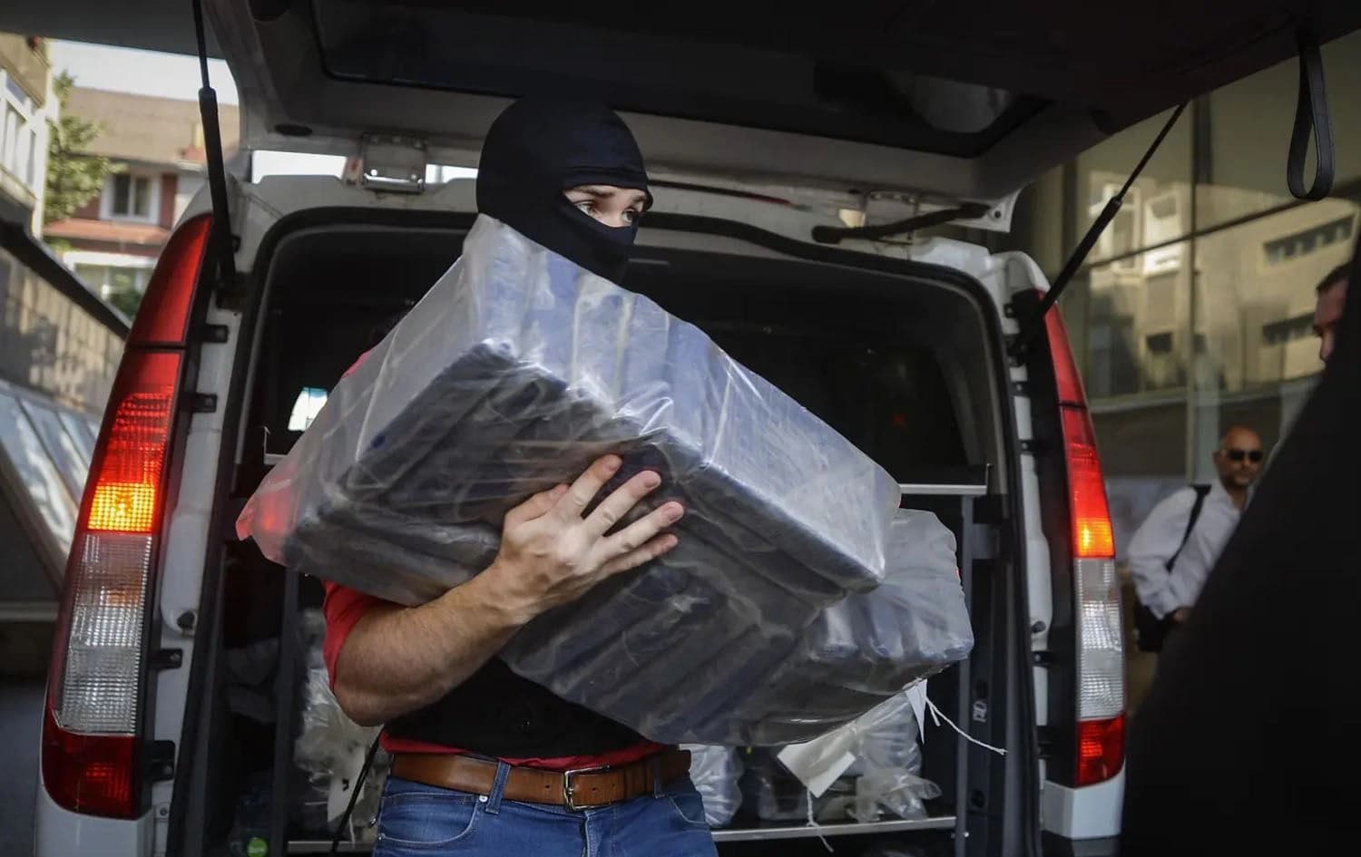 A masked policeman carries packs of cocaine, at the organized crime prosecutor’ office in Bucharest, Romania, on July 1, 2016. File photo: Andreea Alexandru/AP Photo