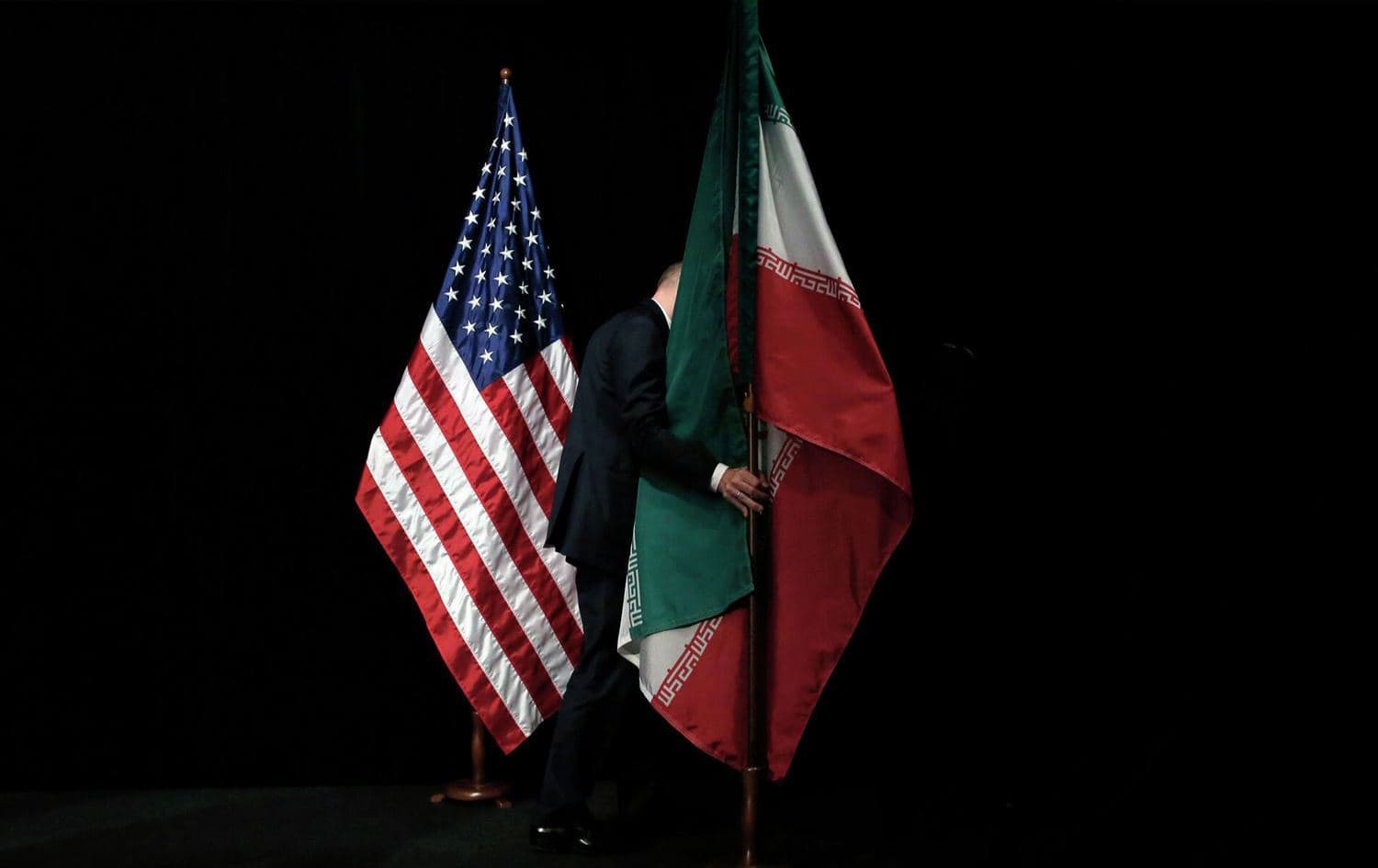 A staff member removes the Iranian flag from the stage after a group picture of foreign ministers and representatives of Unites States, Iran, China, Russia, Britain, Germany, France and the European Union during the nuclear talks at Austria International Centre in Vienna, Austria, on July 14, 2015. Photo: AFP