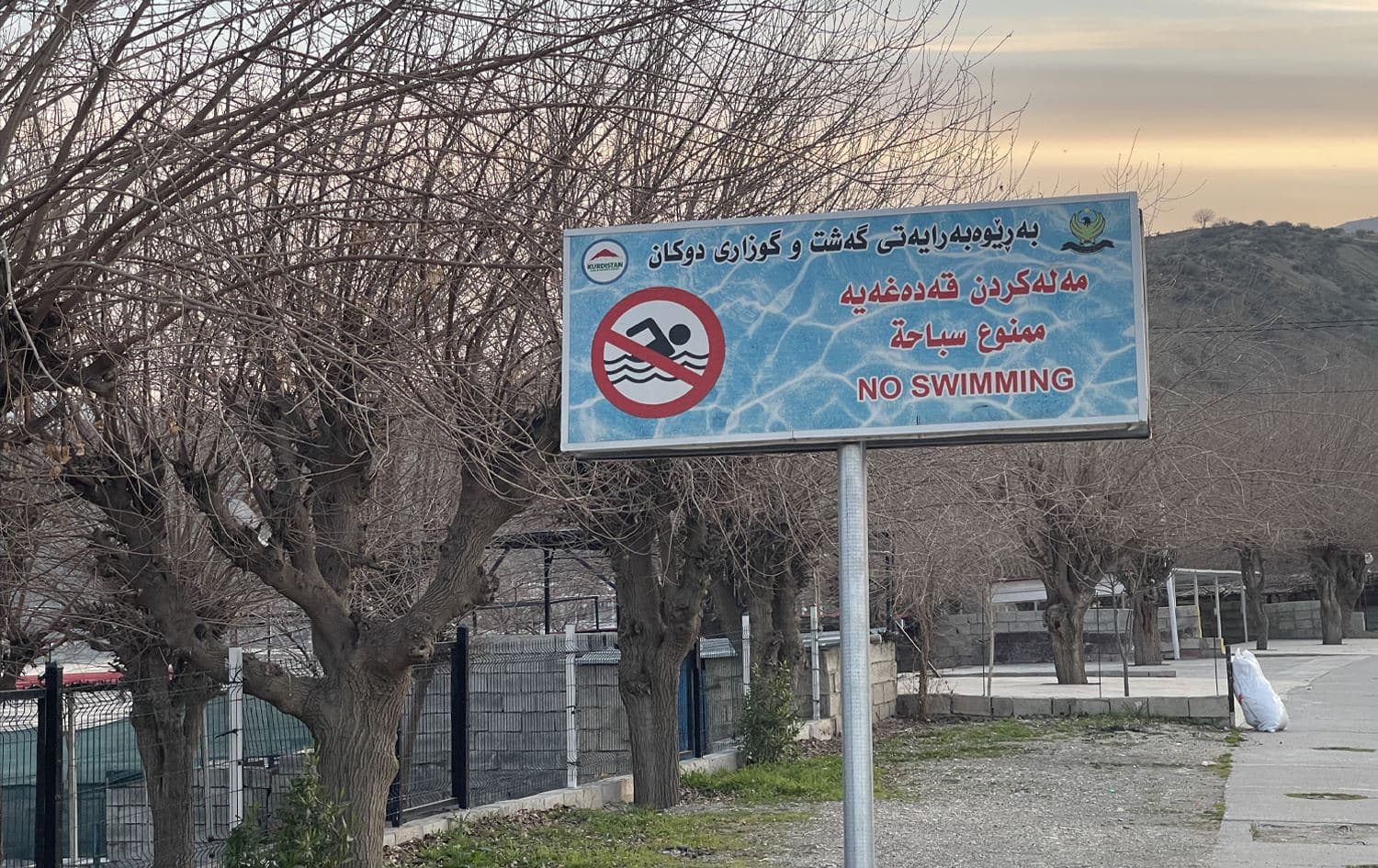لە لێواری رووباری زێی بچووک کە بە دووکاندا دەڕوات لەسەر تابلۆیەک نووسراوە: مەلەکردن قەدەخەیە. وێنە: دڵزار زوبێر - رووداو