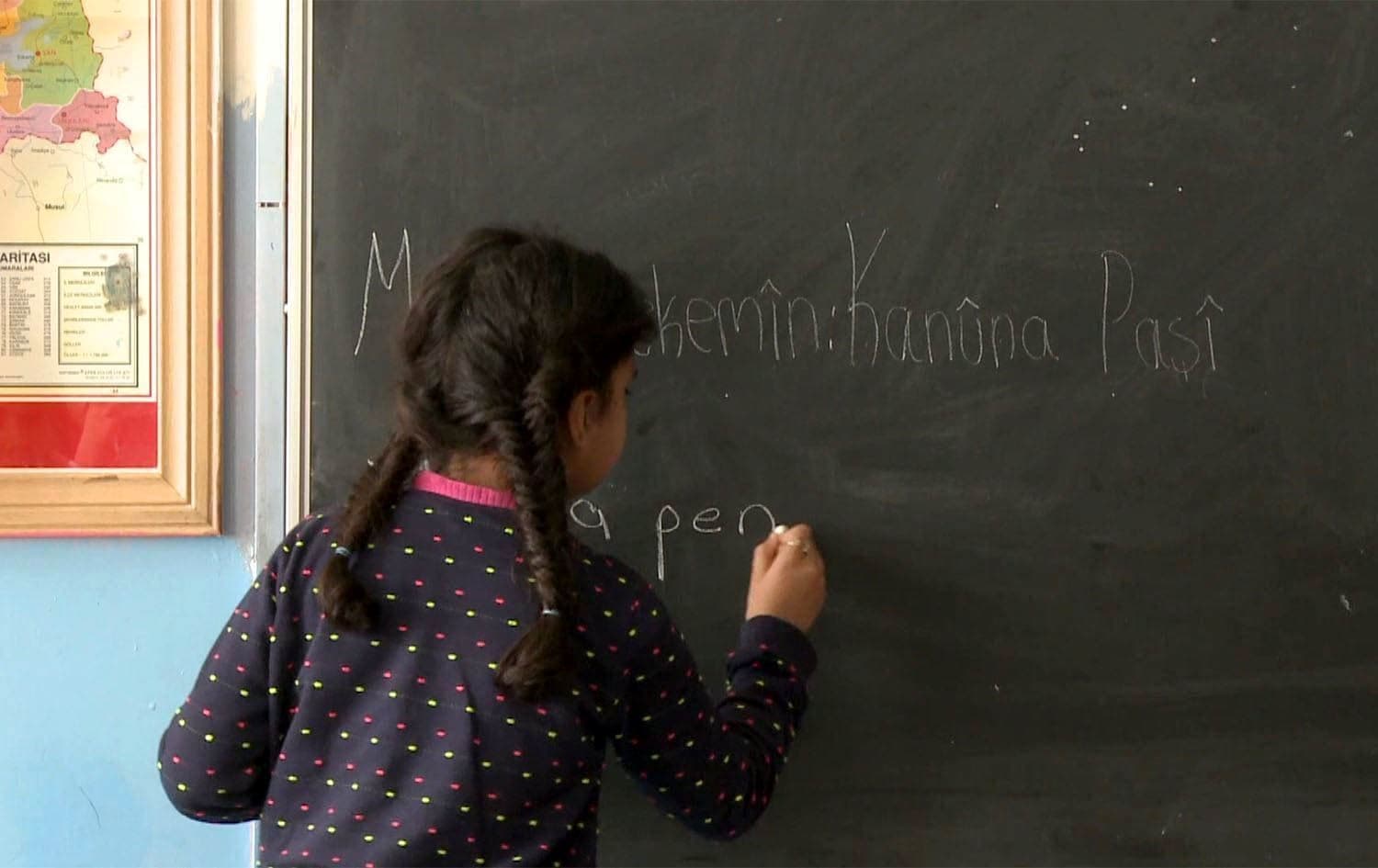 کیژێک لەسەر تەختەڕەش بە کوردی دەنووسێت. 